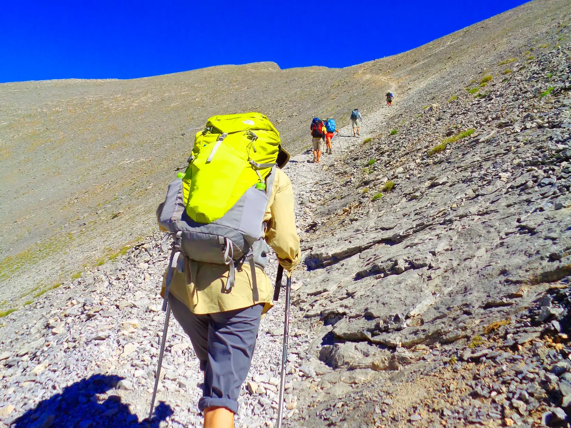 Wandergruppe beim Trekking-Aufstieg auf einem felsigen Pfad zum Gipfel Skolio im griechischen Olymp-Massiv.