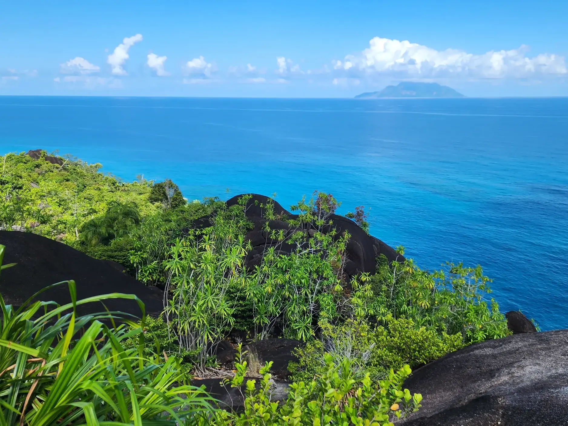 Aussichtspunkt auf einer Wanderung auf Mahé mit Blick über Granitfelsen auf den Indischen Ozean und Silhouette Island.