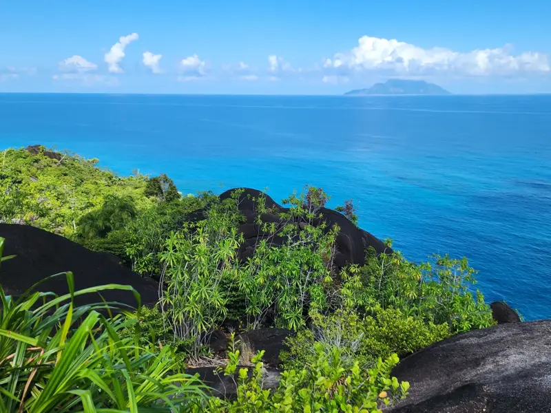 Aussichtspunkt auf einer Wanderung auf Mahé mit Blick über Granitfelsen auf den Indischen Ozean und Silhouette Island.