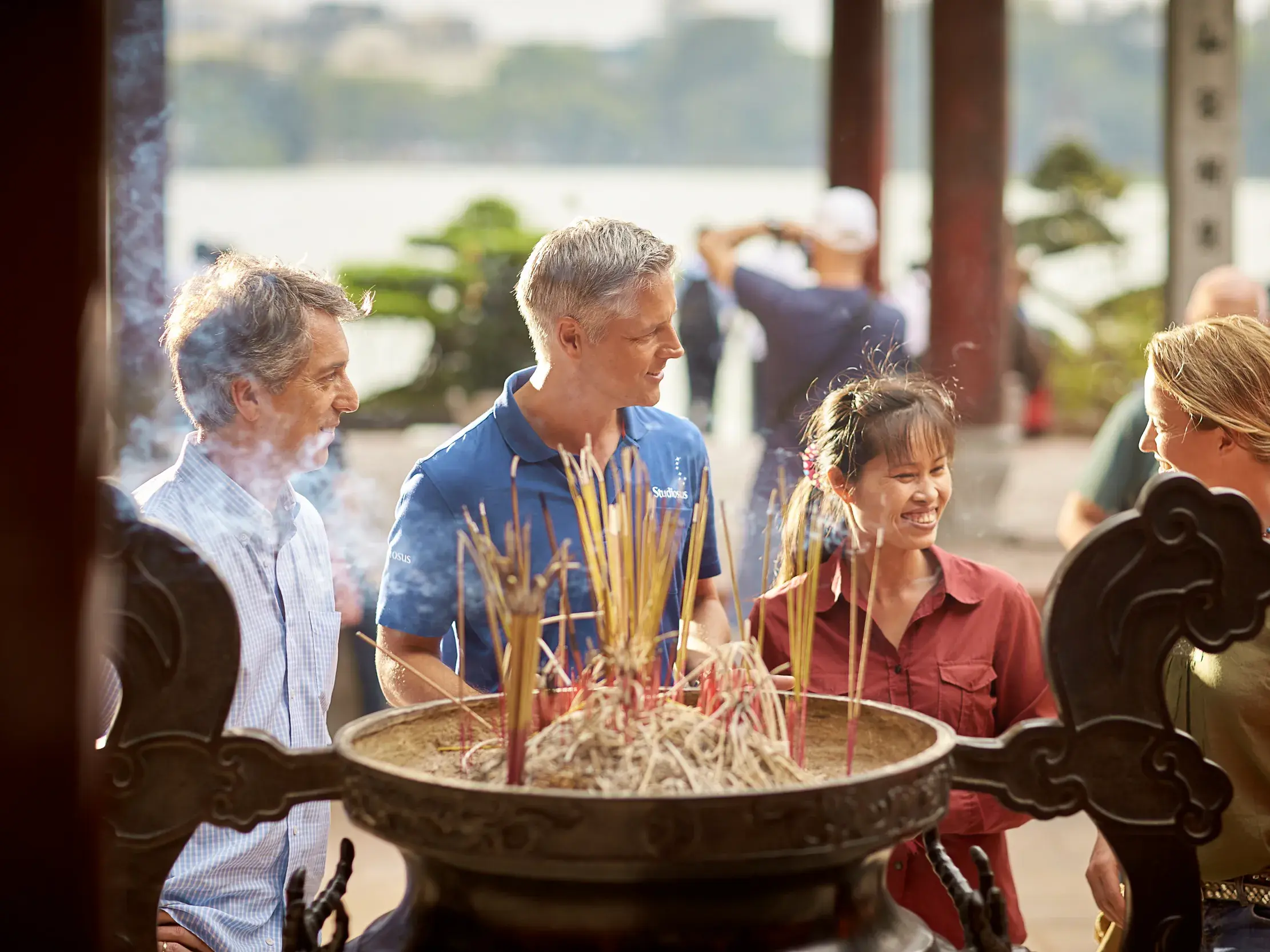 Teilnehmer einer Studiosus-Studienreise lernen von ihrem Reiseleiter die Bedeutung von Räucherstäbchen in einem Tempel in Hanoi.