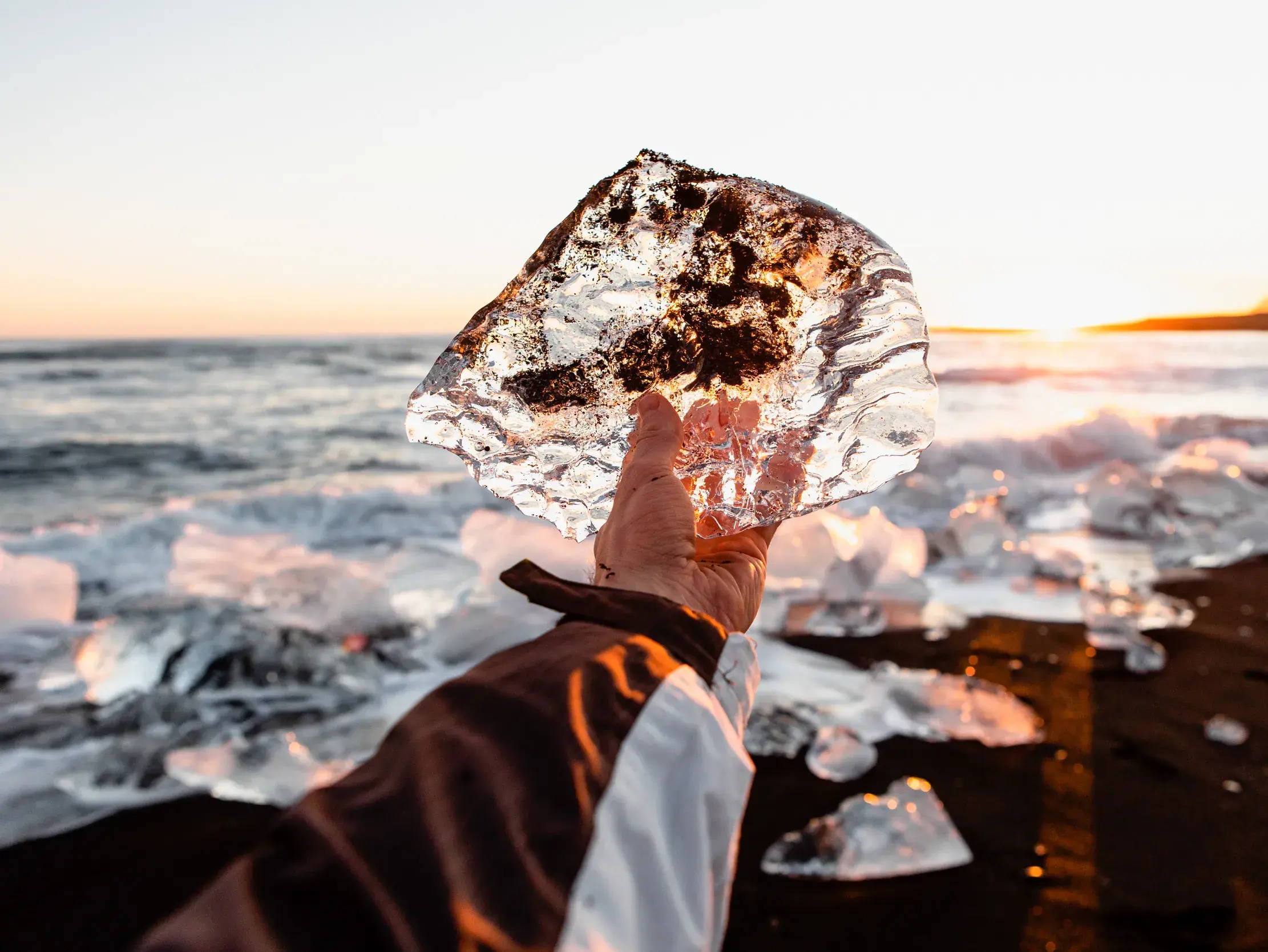 Ein glitzernder Eisbrocken am schwarzen Sand des Diamond Beach in Island