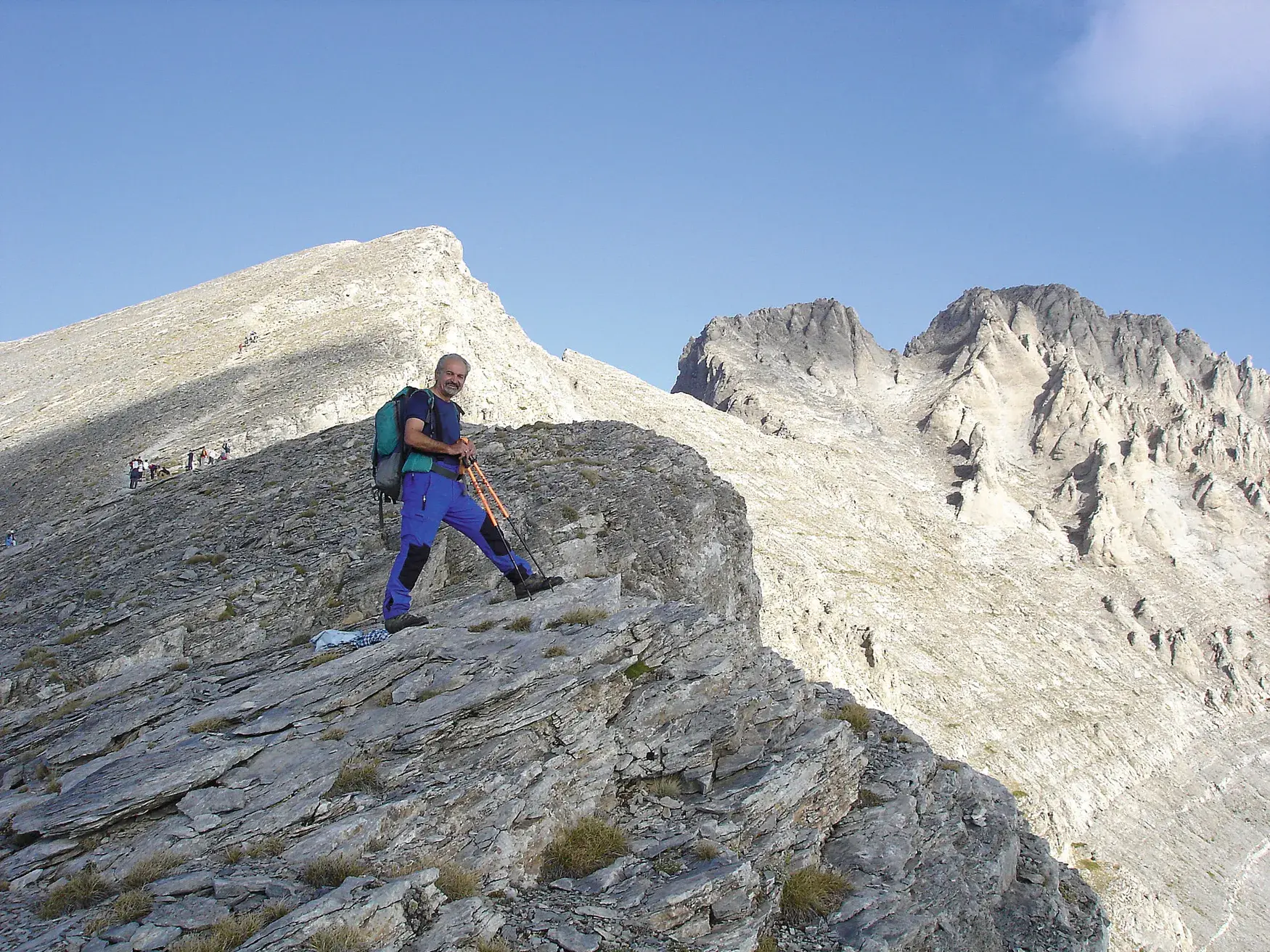 Ein Wanderer mit Rucksack pausiert auf einem Felsgrat während der Hauser Trekkingtour zum Gipfel Skolio im Olymp-Massiv.