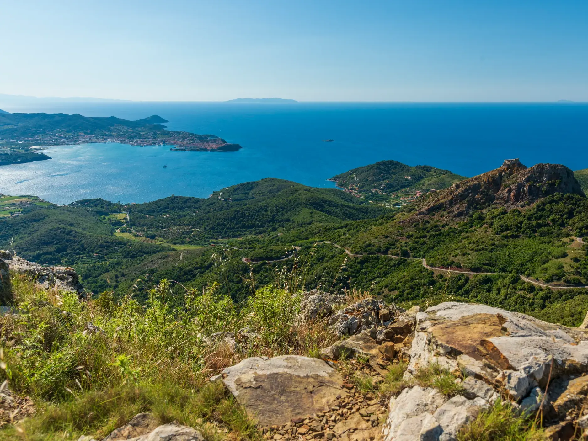 Spektakuläre Aussicht beim Trekking auf dem GTE über die grüne Küstenlandschaft Elbas zur Bucht von Portoferraio.