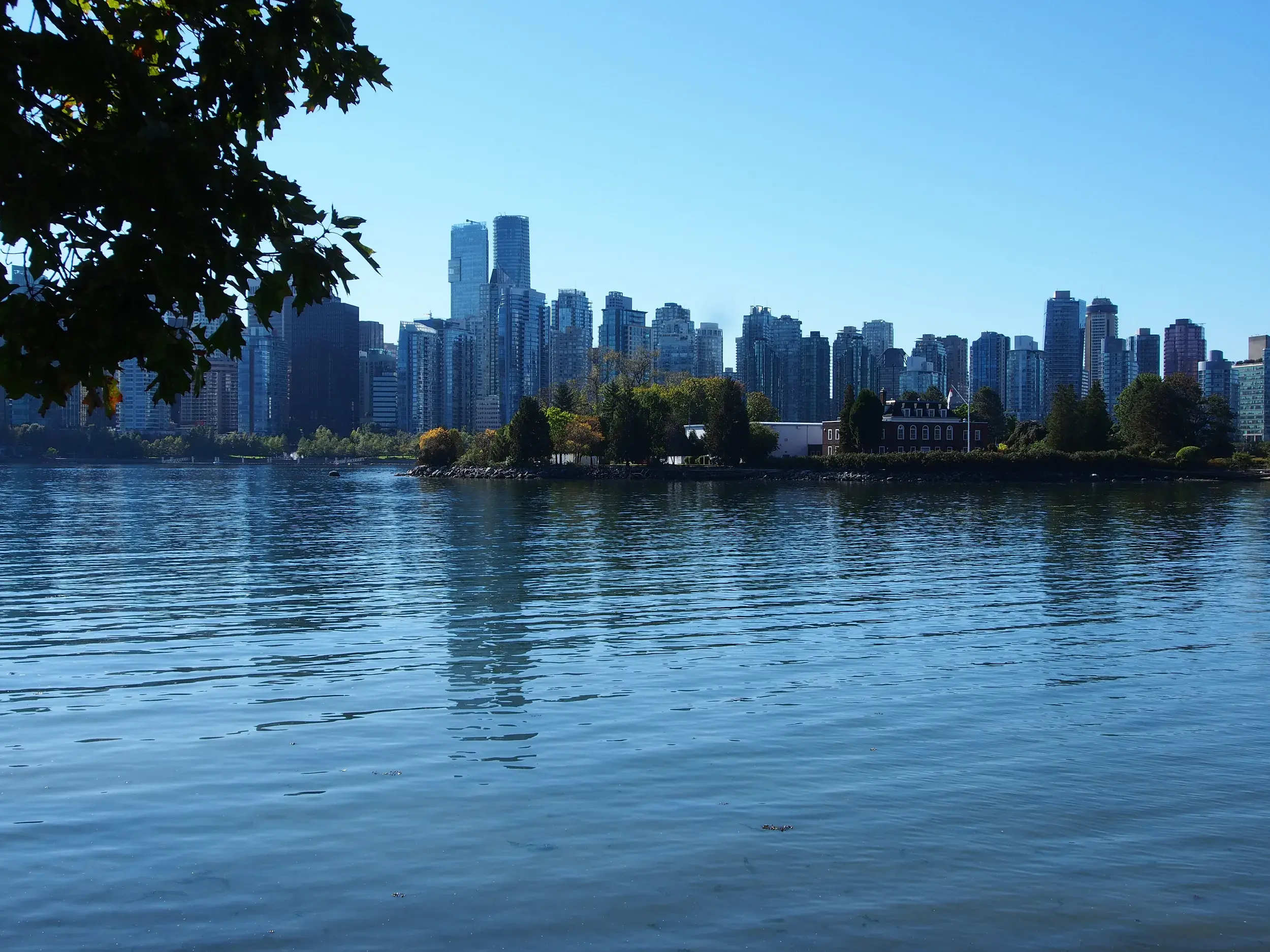 Blick vom Stanley Park über das Wasser auf die sonnige Skyline der Metropole Vancouver in Kanada.