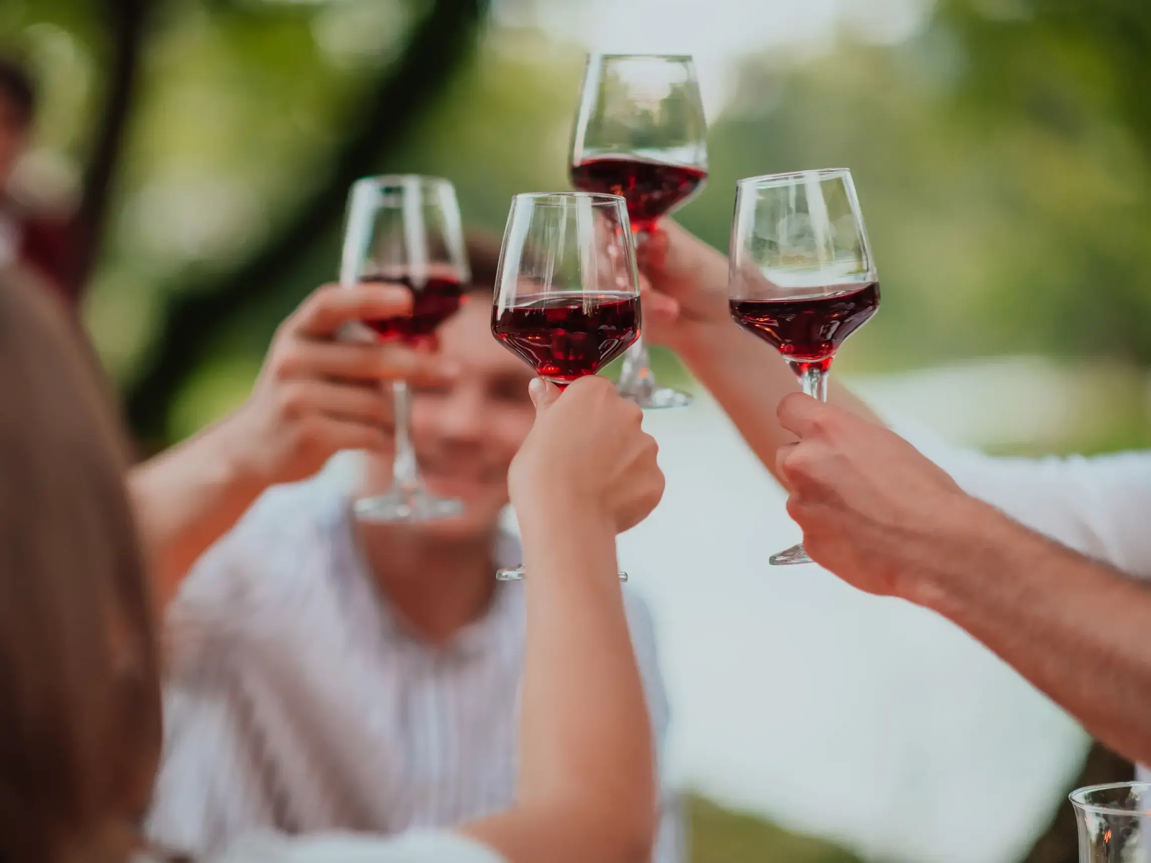 Eine kleine Gruppe stößt bei einer Weinprobe auf der Azoreninsel Pico mit Gläsern voller Rotwein an.