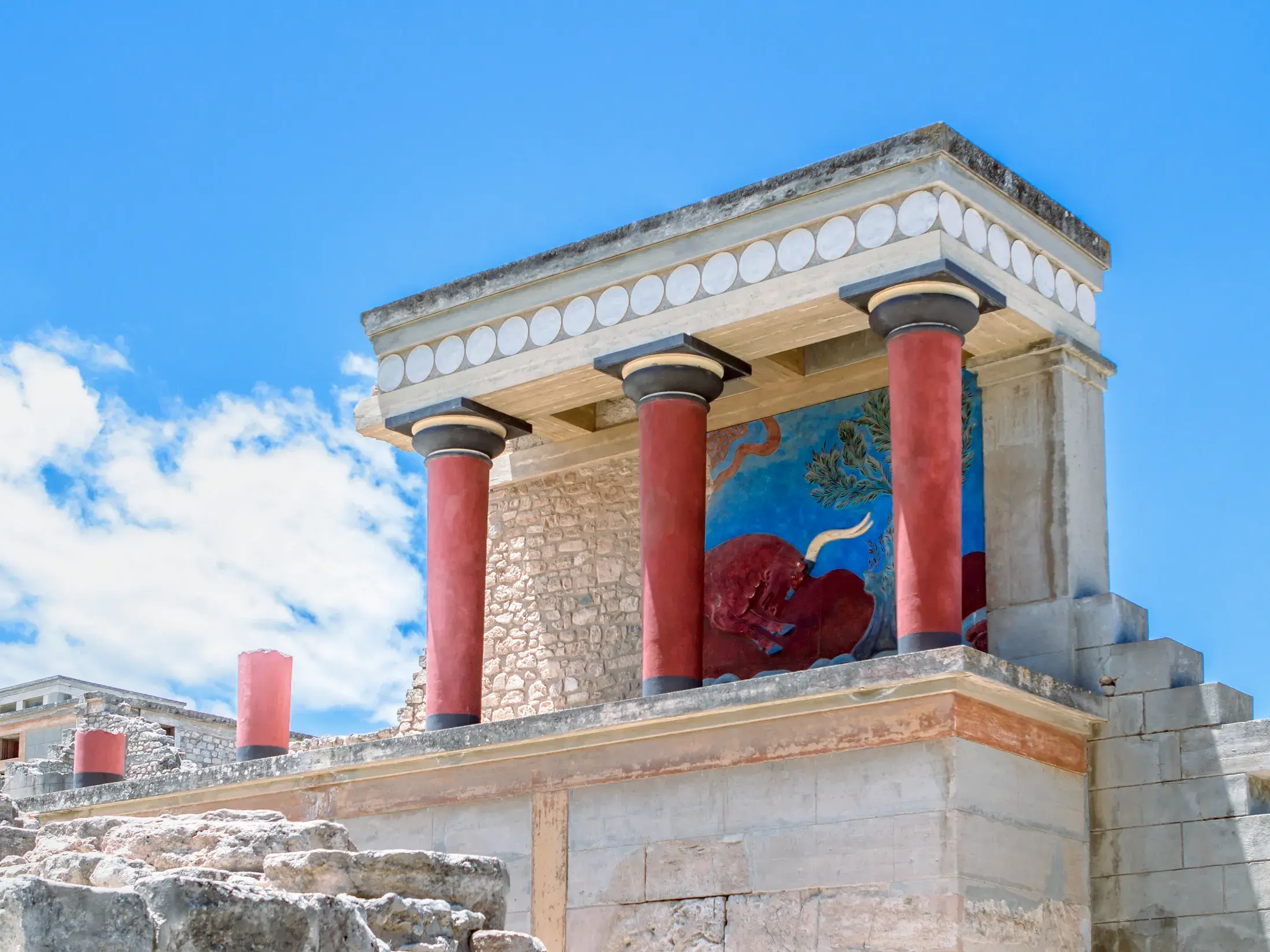 Der teilweise rekonstruierte Nordeingang des Palastes von Knossos auf Kreta mit seinen markanten roten Säulen und dem Stier-Fresko.