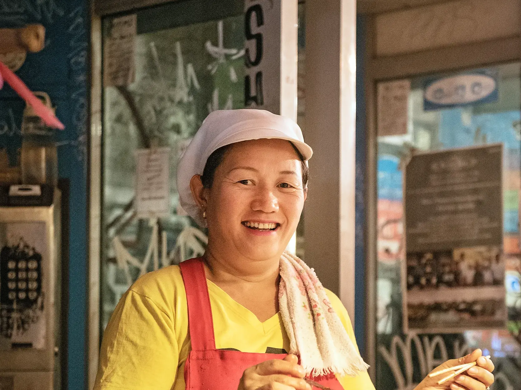 Eine freundliche, thailändische Garküchen-Köchin lächelt während einer Studiosus-Studienreise in die Kamera.