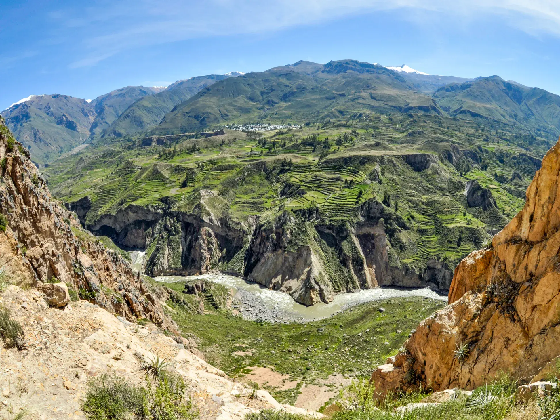 Atemberaubender Panoramablick auf den Colca-Canyon in Peru mit grünen Terrassen, dem Fluss im Tal und den Anden am Horizont.