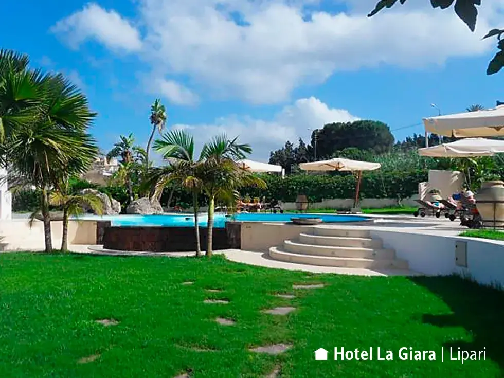 Sonnige Gartenanlage mit Swimmingpool, Palmen und Sonnenschirmen im Hotel Residence La Giara auf der Insel Lipari.