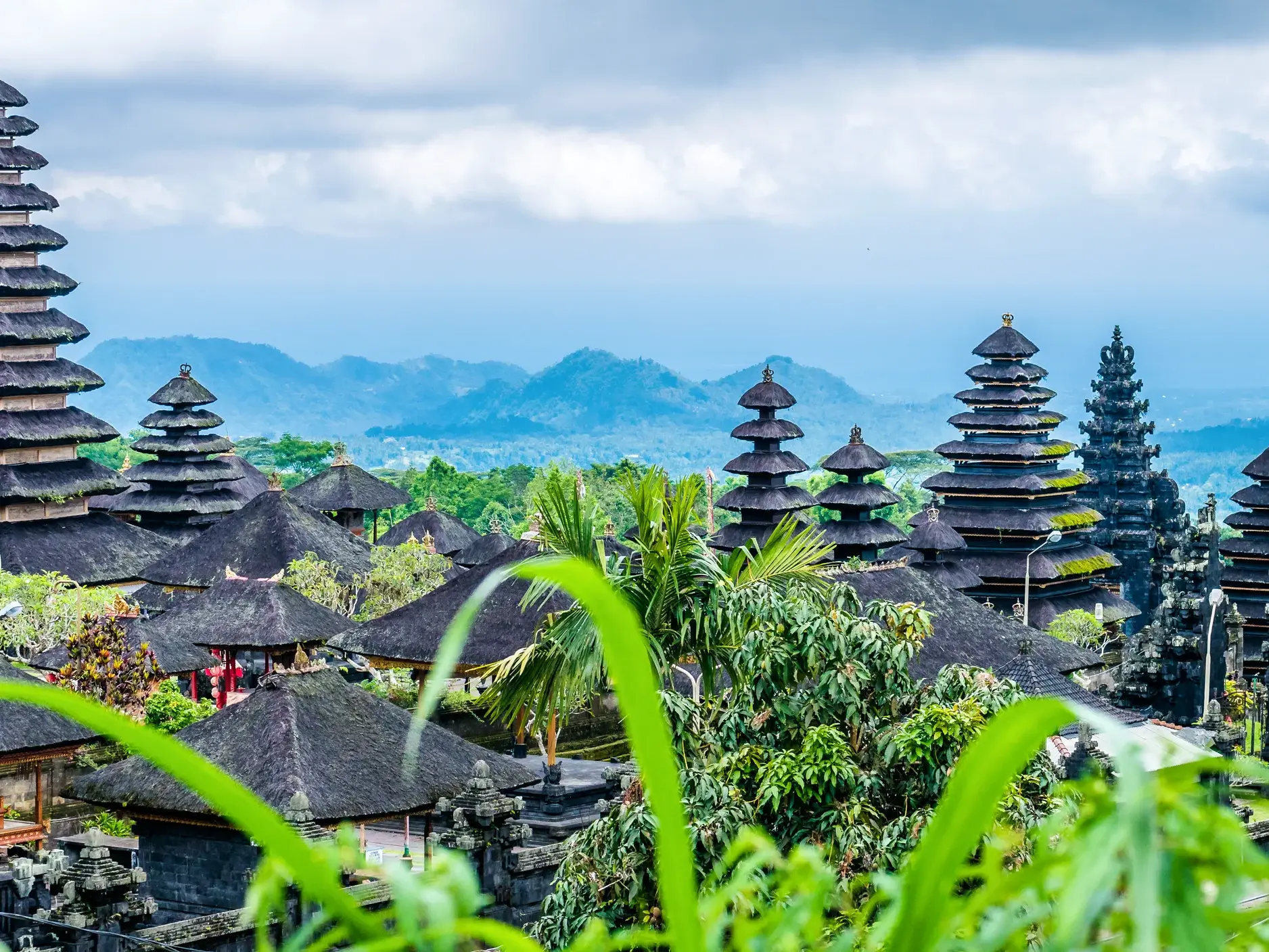 Die weitläufige Anlage des Muttertempels Besakih auf Bali mit ihren typischen mehrstufigen Dächern vor tropischer Bergkulisse.