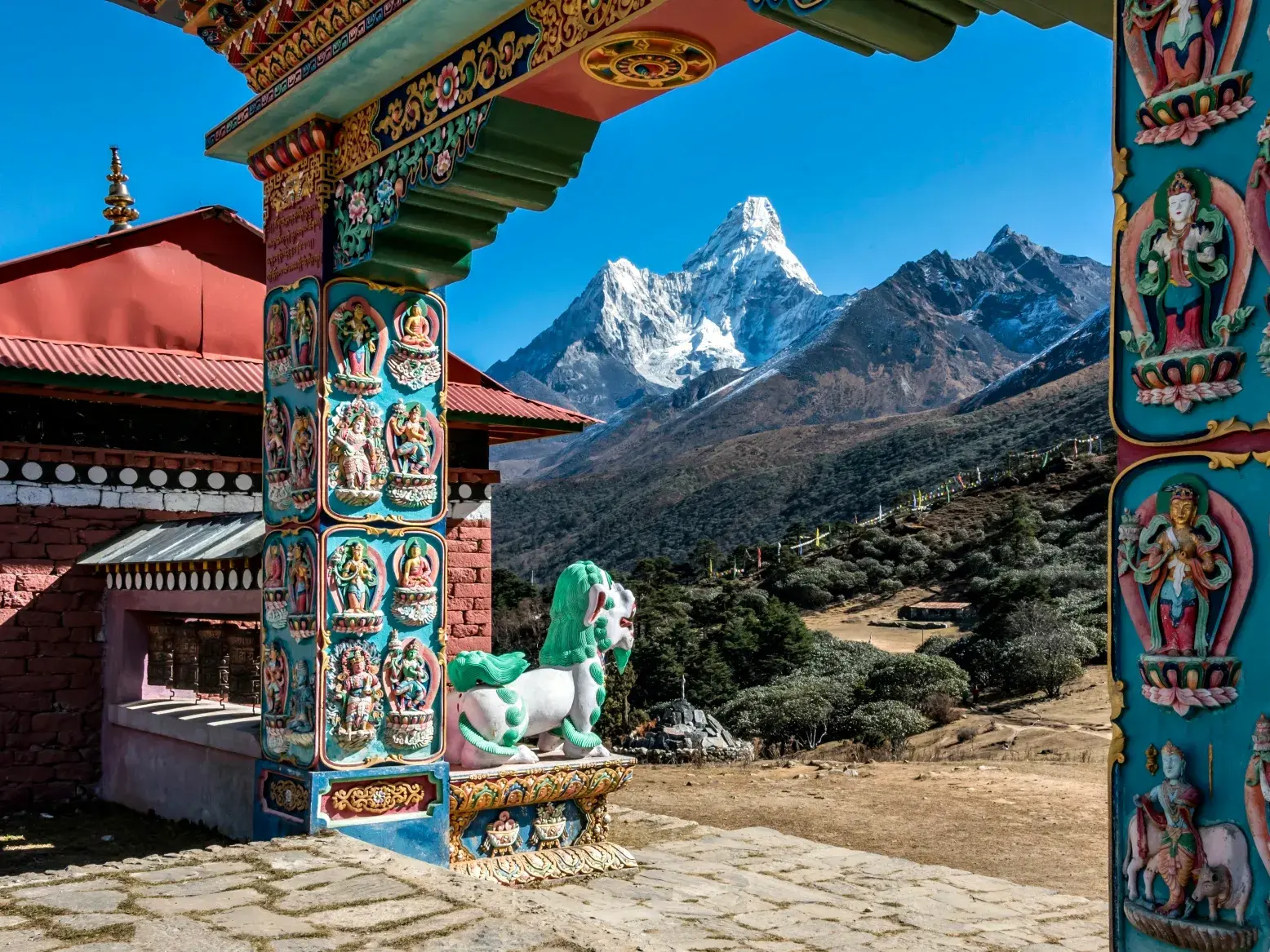 Blick durch das verzierte Eingangstor des Klosters Tengboche auf den schneebedeckten Gipfel des Ama Dablam in Nepal.
