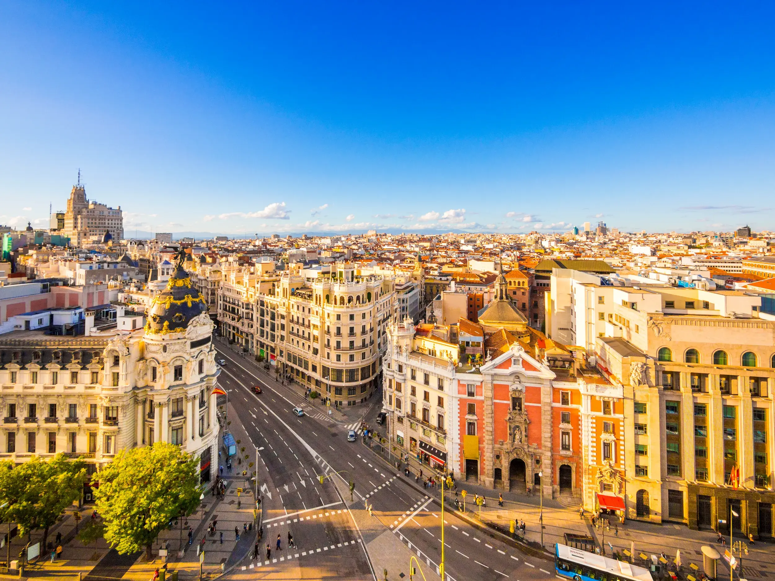 Weitblick vom Círculo de Bellas Artes über Madrids Prachtbauten und die belebte Calle de Alcalá bei strahlend blauem Himmel.
