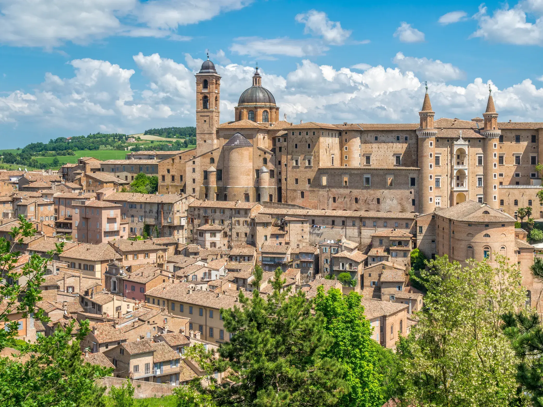 Panoramablick auf die Renaissancestadt Urbino mit dem imposanten Palazzo Ducale und Dom unter blauem Himmel in den Marken.