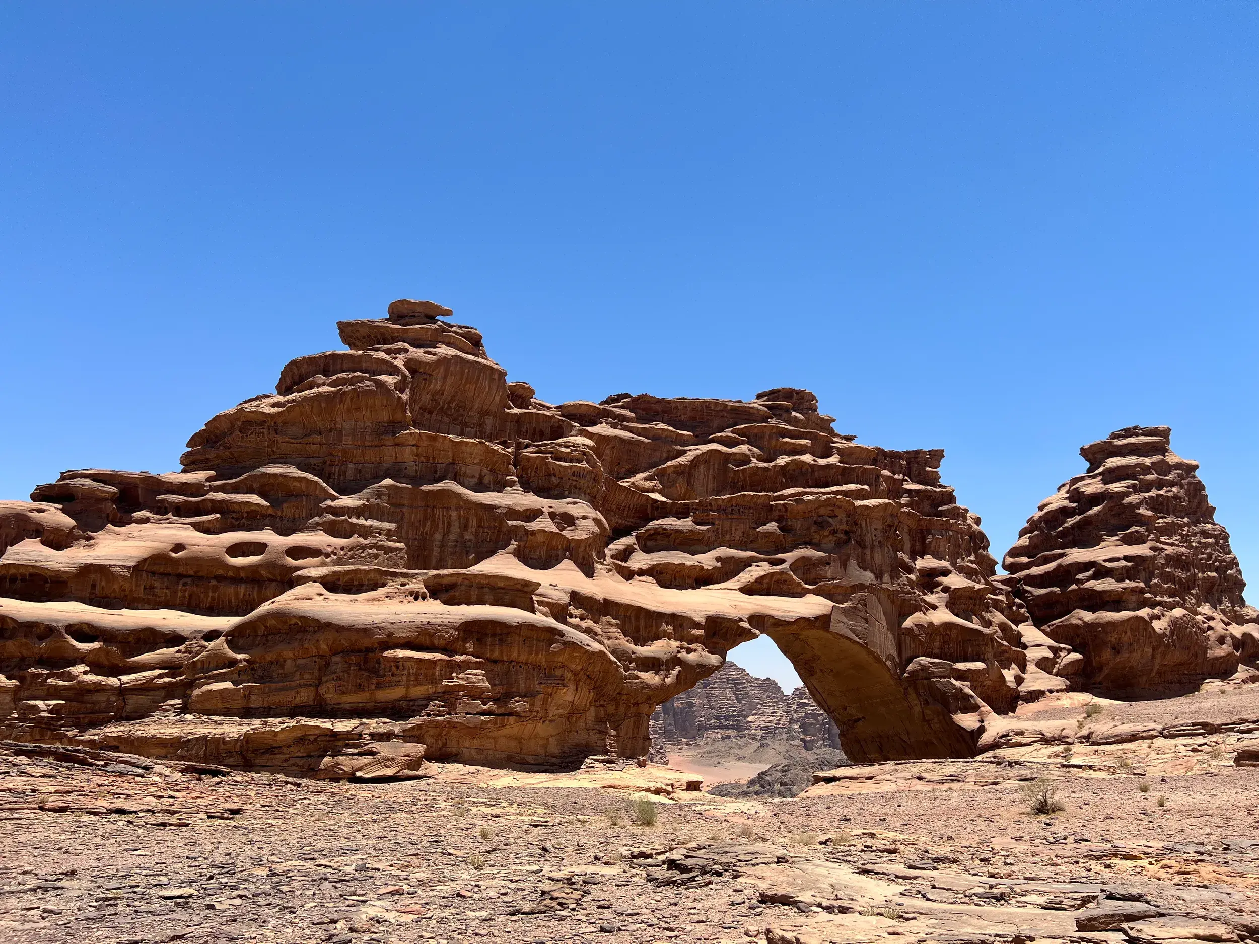 Majestätischer Felsbogen, der Große Bogen, in der weiten Hisma-Wüste Saudi-Arabiens unter strahlend blauem Himmel.