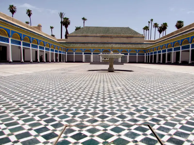 Der berühmte Innenhof des Bahia-Palasts in Marrakesch mit aufwendigen Mosaiken, einem Brunnen und umlaufenden Säulengängen.