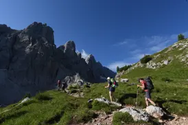 Eine Wandergruppe beim Trekking auf dem Höhenweg Alta Via 1 in den Dolomiten, vorbei an steilen Felswänden.