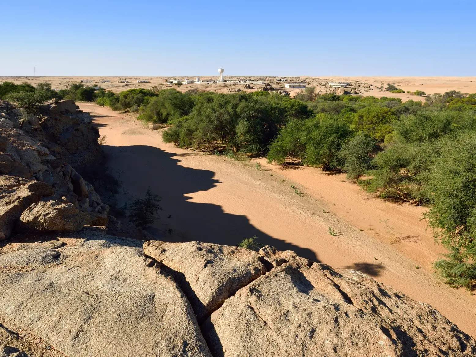 Weite Sicht von felsiger Anhöhe auf das trockene Kuiseb Rivier mit Galeriewald bei der Gobabeb Forschungsstation in Namibia.