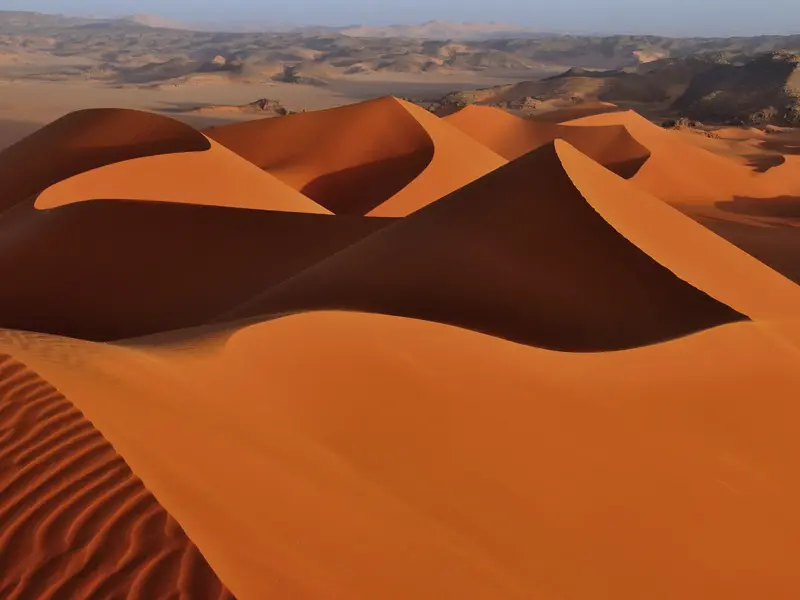 Majestätische, goldene Sanddünen unter weitem Himmel im Tadrart, dem Herz der algerischen Sahara-Wüste.