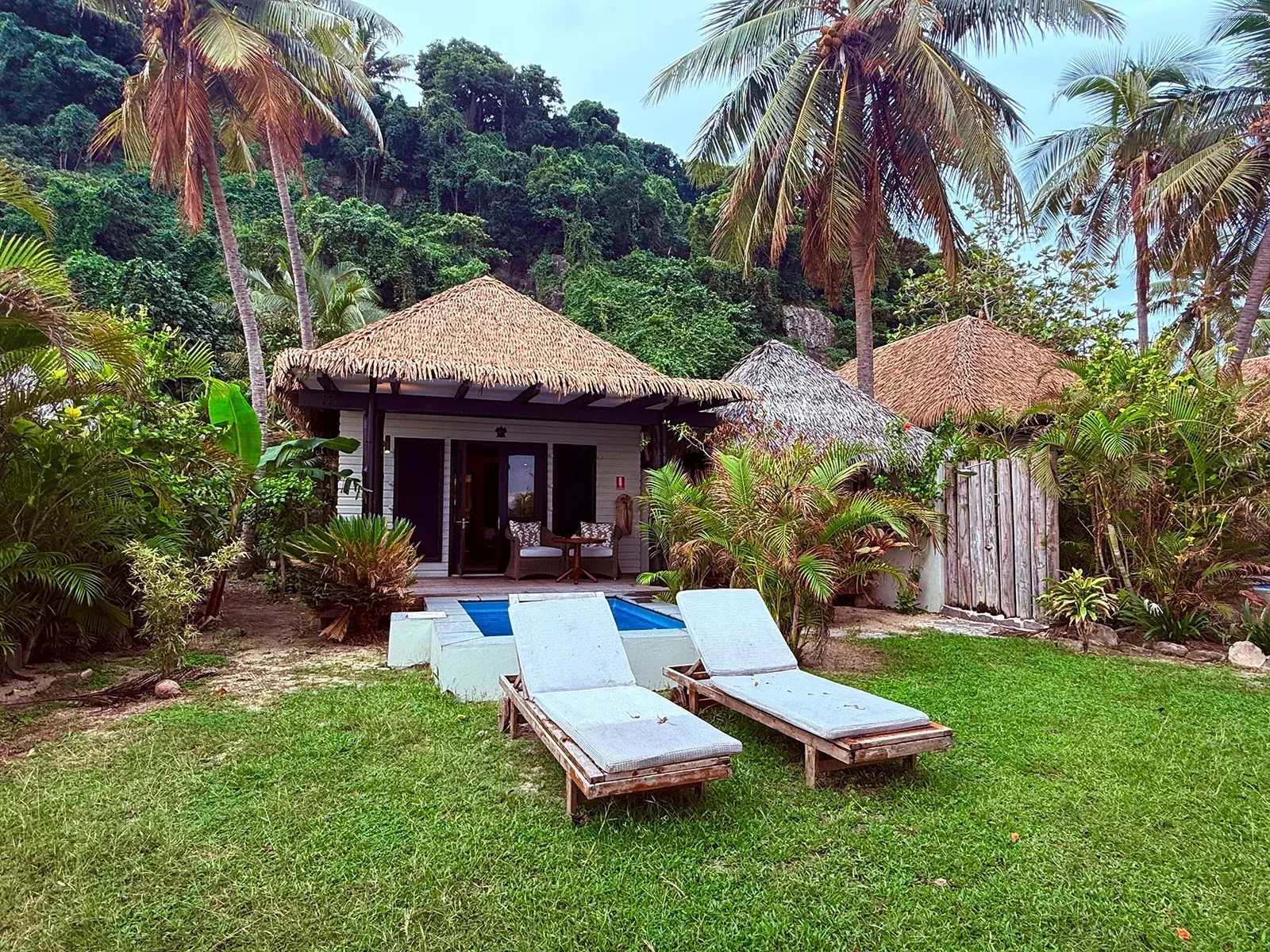 Idyllischer Bungalow mit Strohdach und Privatpool im Matamanoa Insland Resort in Fiji auf den Mamanuca-Inseln umgeben von Palmen und Regenwald.