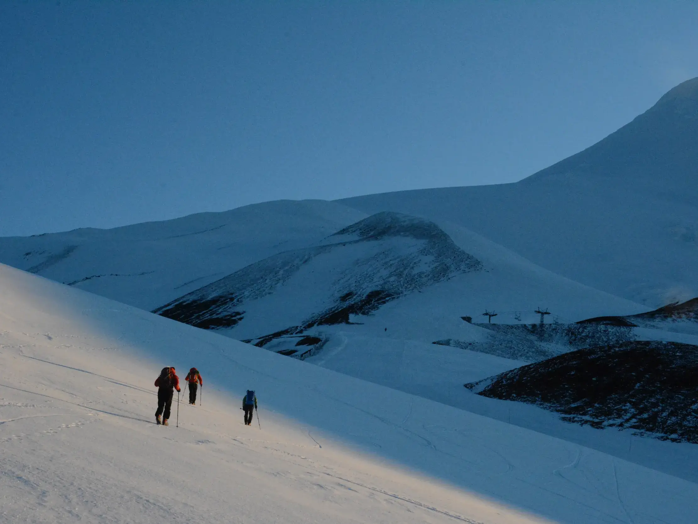 Eine Trekkinggruppe steigt im Morgenlicht einen weiten, schneebedeckten Hang am Vulkan Osorno in Nordpatagonien hinauf.