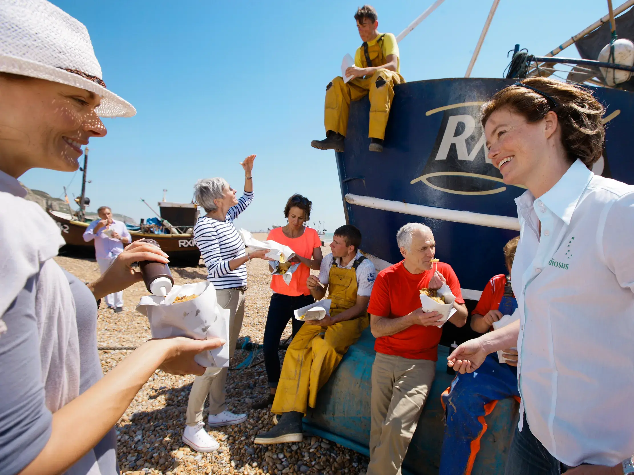 Eine Studiosus-Reiseleiterin genießt mit ihrer Gruppe eine Mittagspause mit Fish & Chips am Kieselstrand von Weymouth.