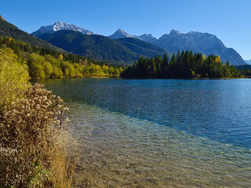Beim Isar-Trekking: Klares Wasser am Ufer des Wildflusses mit Blick auf die herbstlichen Alpen und das Karwendel.