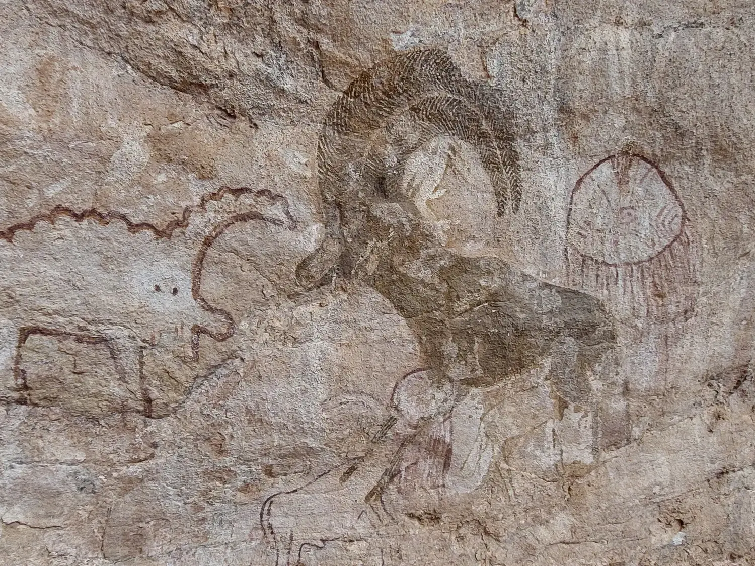 Nahaufnahme prähistorischer Felsmalereien im Tassili n'Ajjer Nationalpark, die einen Widder und weitere Tiere zeigen.