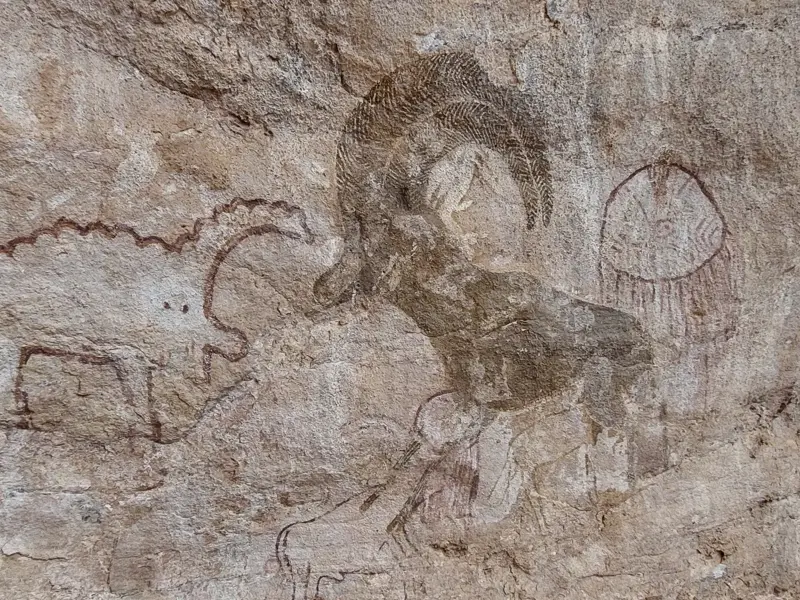 Nahaufnahme prähistorischer Felsmalereien im Tassili n'Ajjer Nationalpark, die einen Widder und weitere Tiere zeigen.