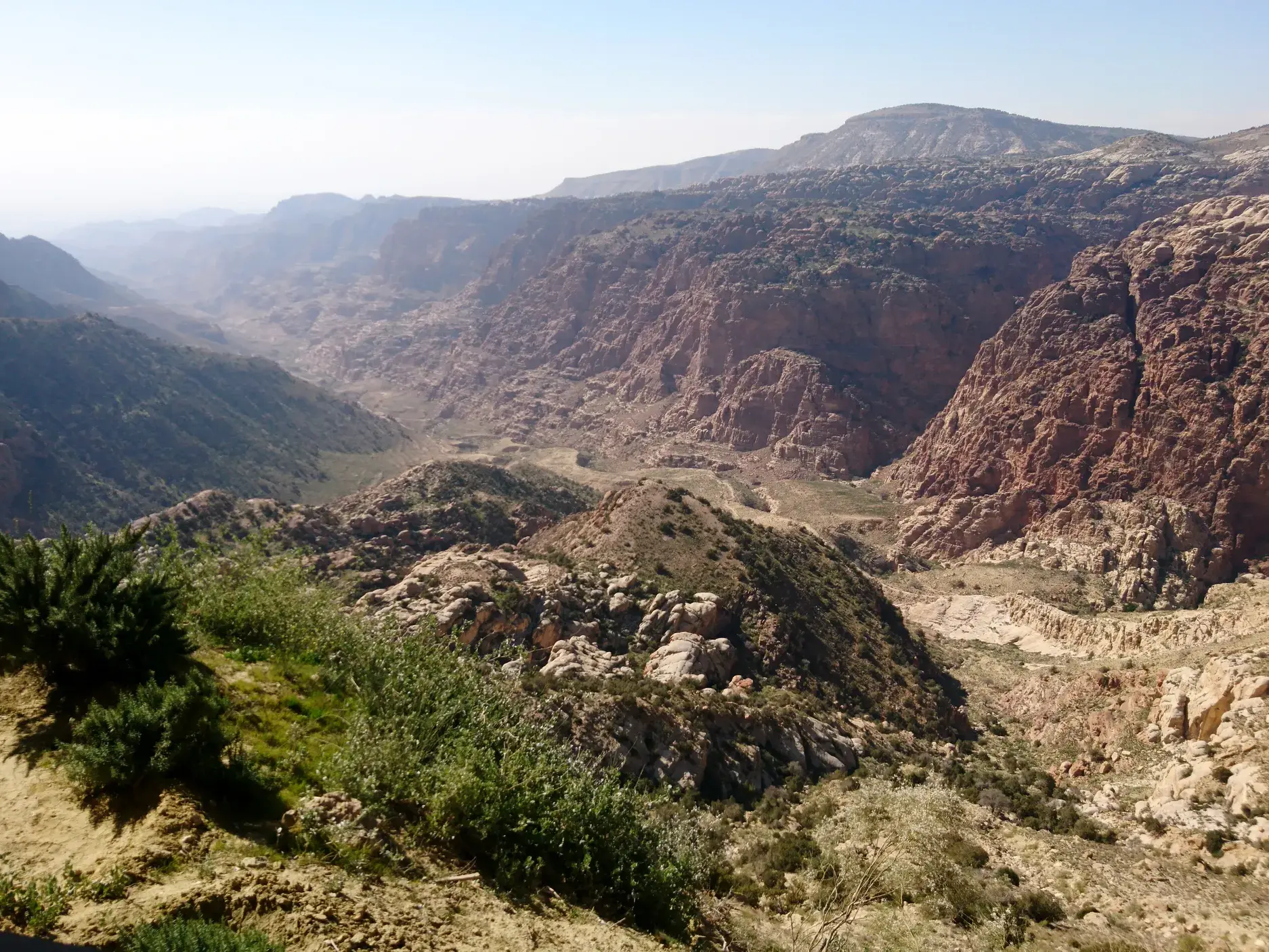 Panoramablick von einem Wanderweg auf die weite, felsige Schlucht des Wadi Dhana im Dhana Nationalpark in Jordanien.