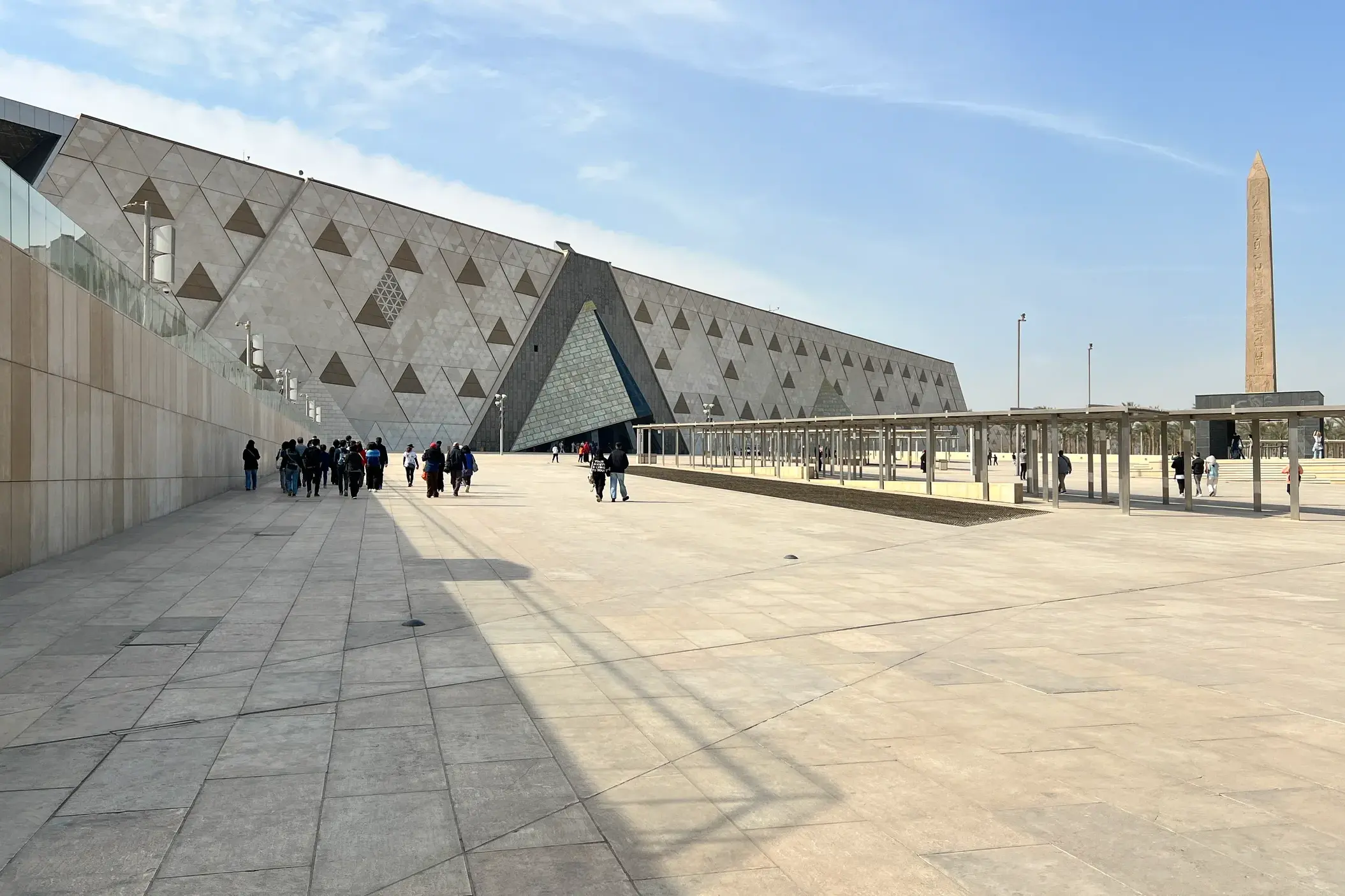 Besucher auf dem Vorplatz des Grand Egyptian Museum in Gizeh mit Obelisk