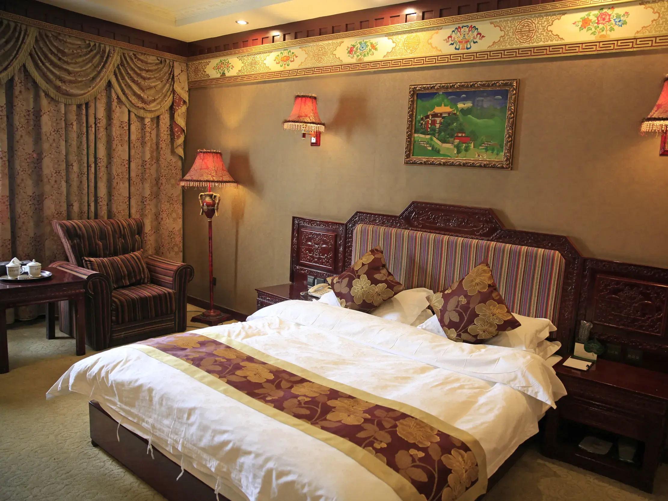 Stilvoll eingerichtetes Zimmer im Hotel Shigayangcha in Shigatse mit traditionellen tibetischen Holzschnitzereien.