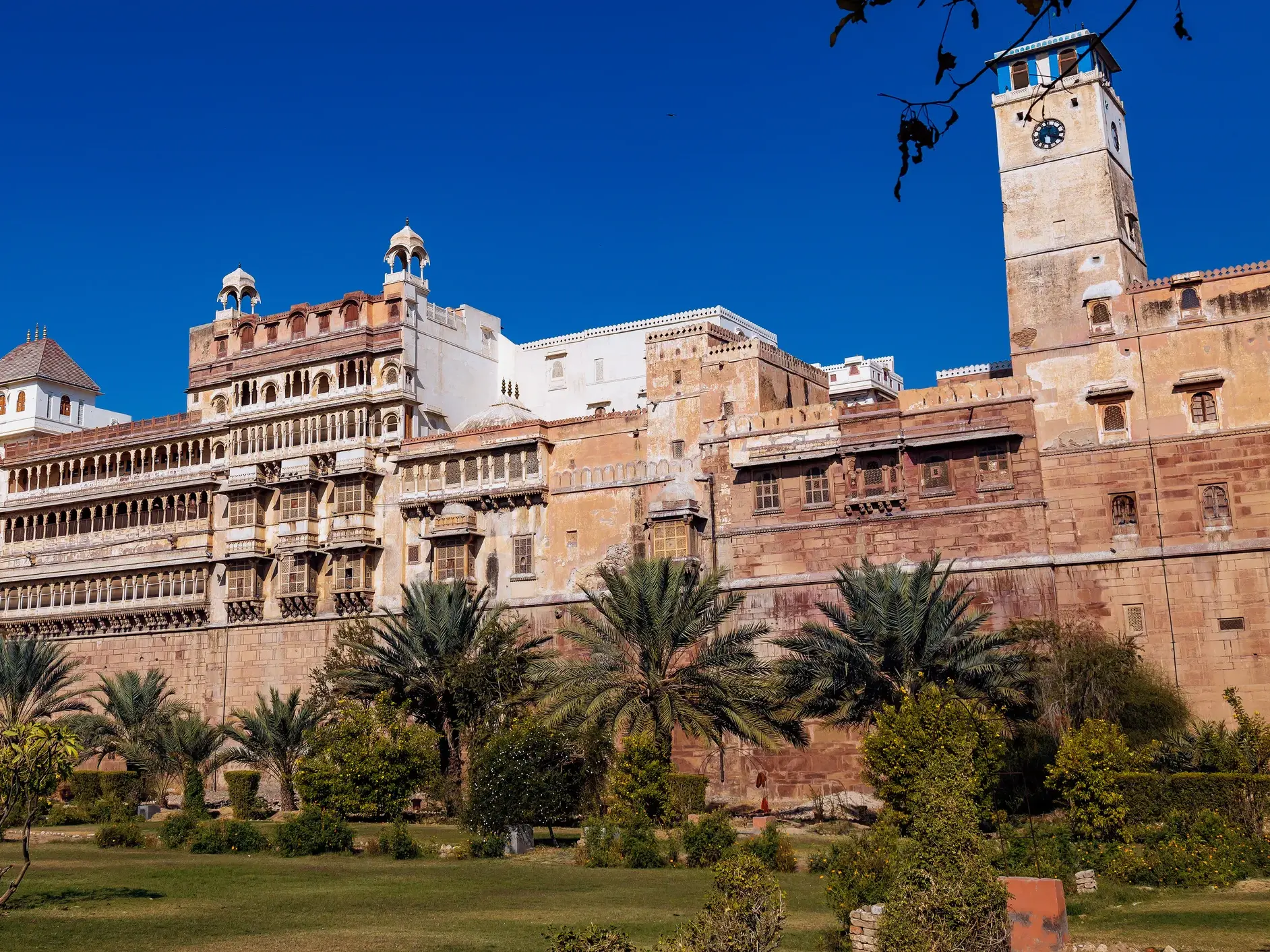 Die weitläufige Festungsanlage des Junagarh Forts in Bikaner mit Uhrturm und Gärten bei strahlend blauem Himmel in Rajasthan.