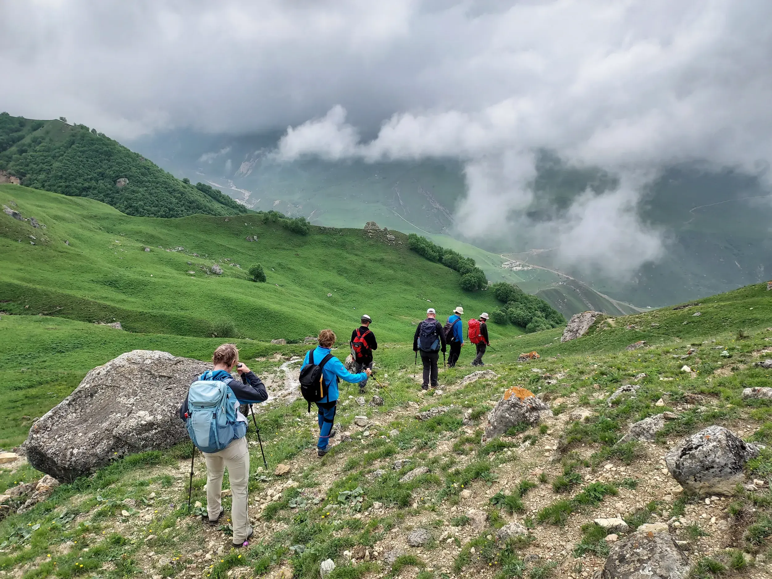 Eine Hauser-Wandergruppe steigt auf einem schmalen Pfad durch die grünen Berge des Großen Kaukasus in Aserbaidschan ab.