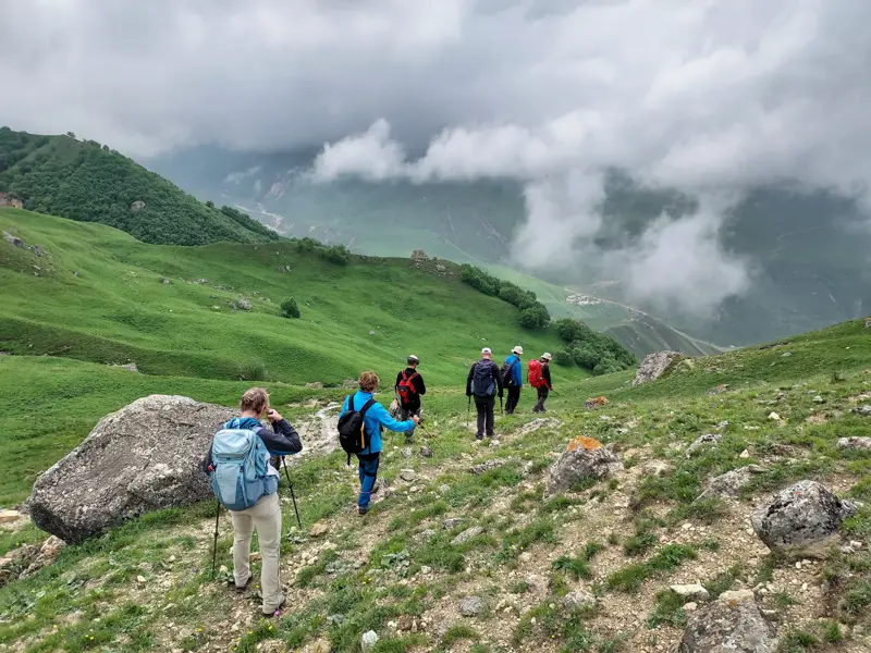 Eine Hauser-Wandergruppe steigt auf einem schmalen Pfad durch die grünen Berge des Großen Kaukasus in Aserbaidschan ab.