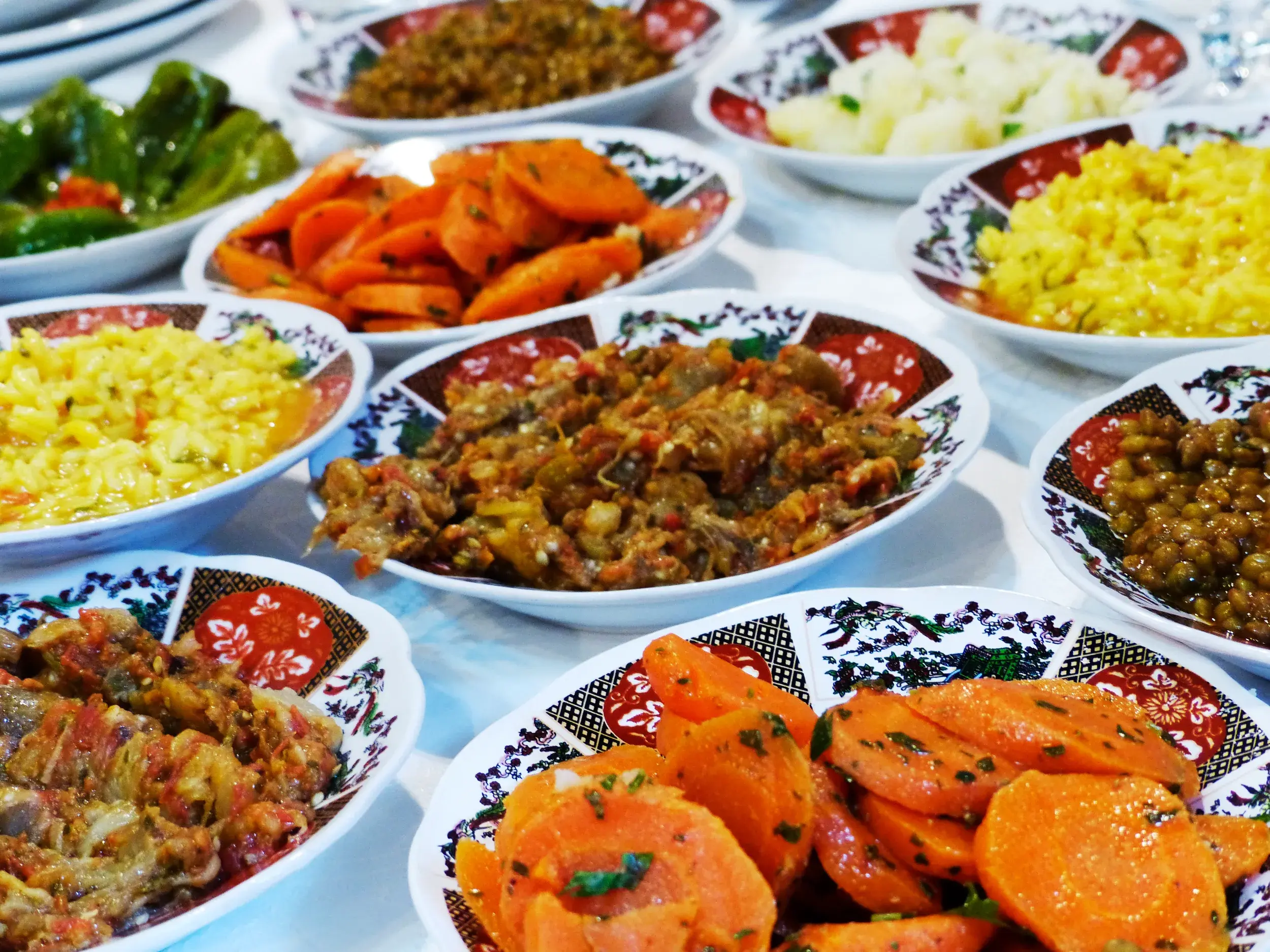 Bunte Auswahl marokkanischer Vorspeisen wie Karottensalat und Zaalouk, serviert in traditionell verzierten Keramikschalen.