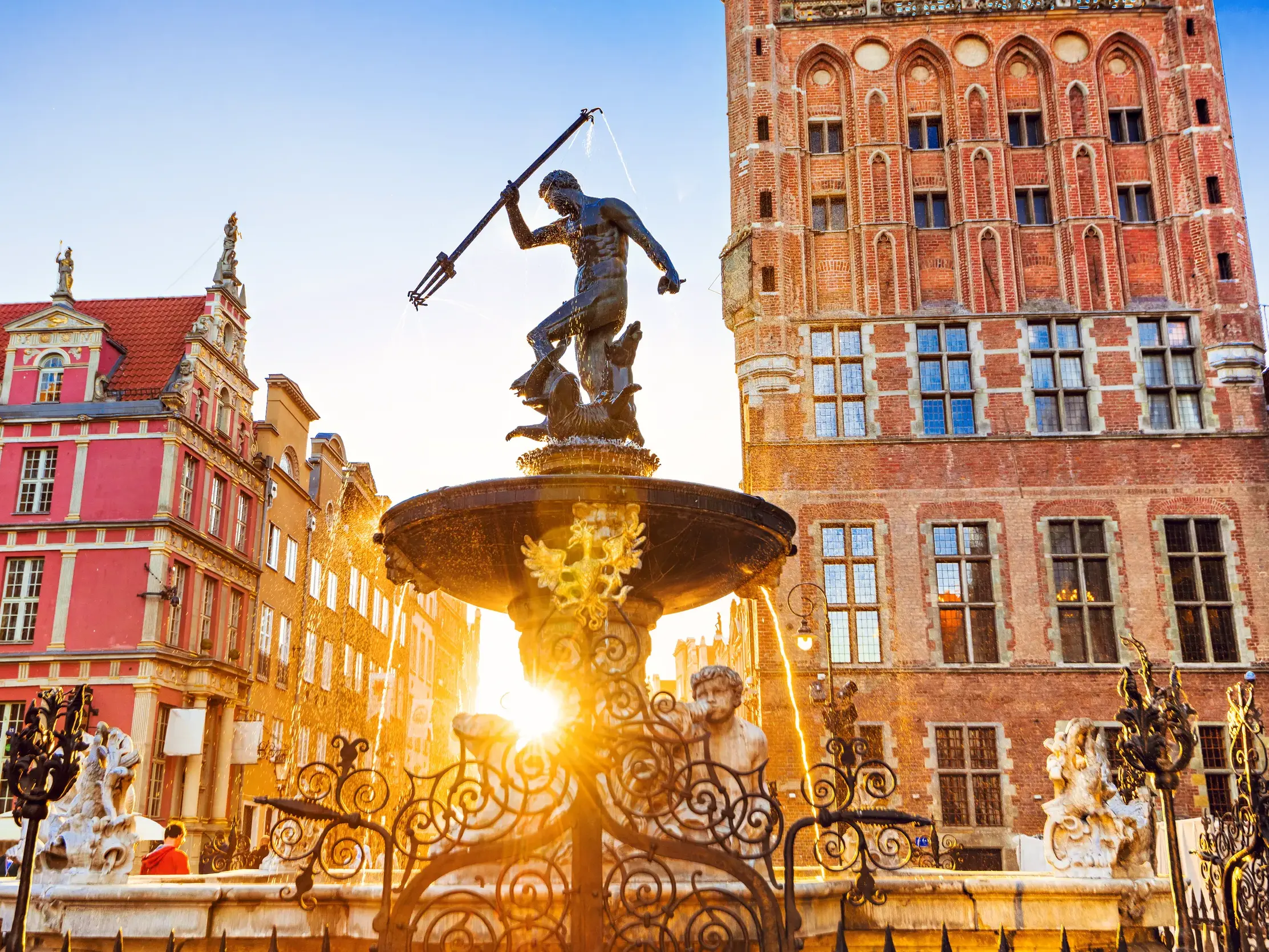 Der Neptunbrunnen in Danzig vor historischen Patrizierhäusern am Langen Markt, in goldenes Abendlicht getaucht.