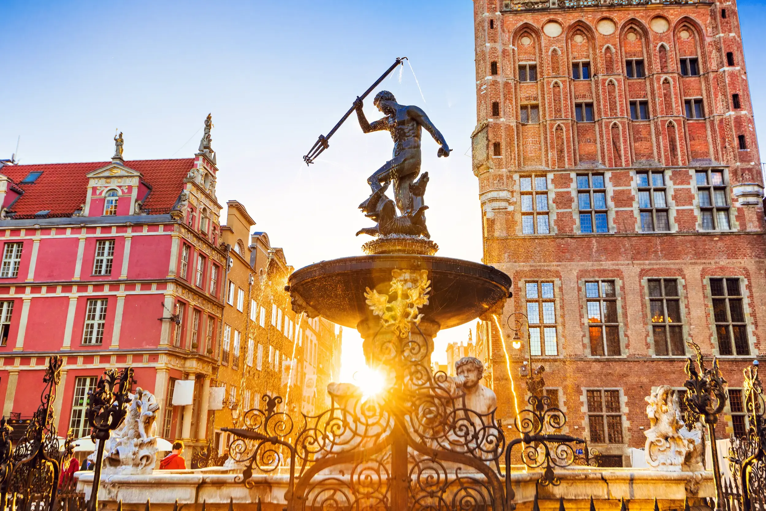 Der Neptunbrunnen in Danzig vor historischen Patrizierhäusern am Langen Markt, in goldenes Abendlicht getaucht.