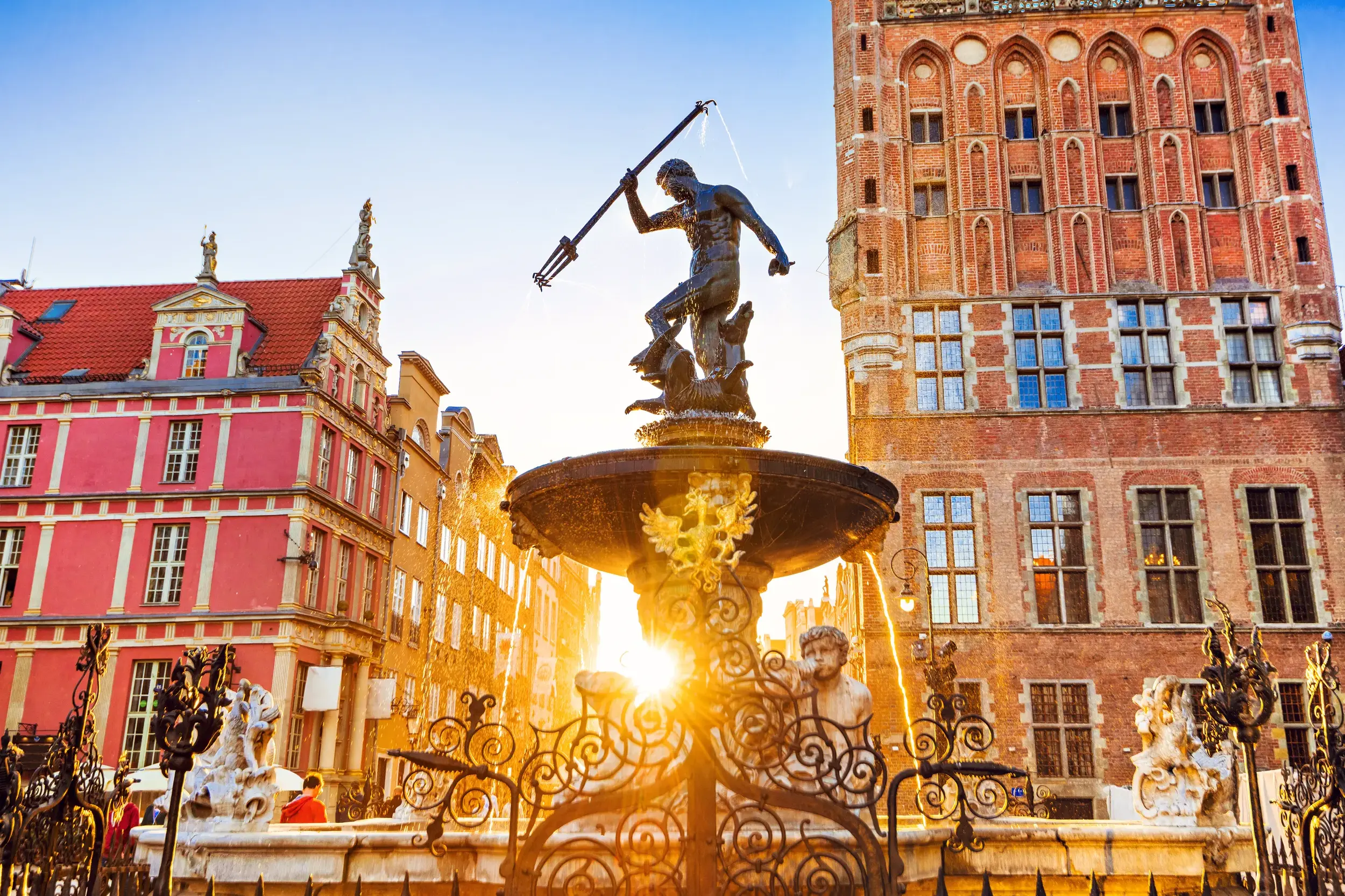 Der Neptunbrunnen in Danzig vor historischen Patrizierhäusern am Langen Markt, in goldenes Abendlicht getaucht.