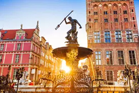 Der Neptunbrunnen in Danzig vor historischen Patrizierhäusern am Langen Markt, in goldenes Abendlicht getaucht.