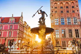 Der Neptunbrunnen in Danzig vor historischen Patrizierhäusern am Langen Markt, in goldenes Abendlicht getaucht.