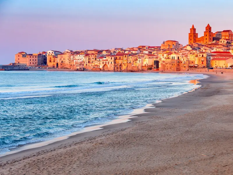 Sandstrand an der Küste mit Blick auf die historische Altstadt und den normannischen Dom von Cefalù auf Sizilien