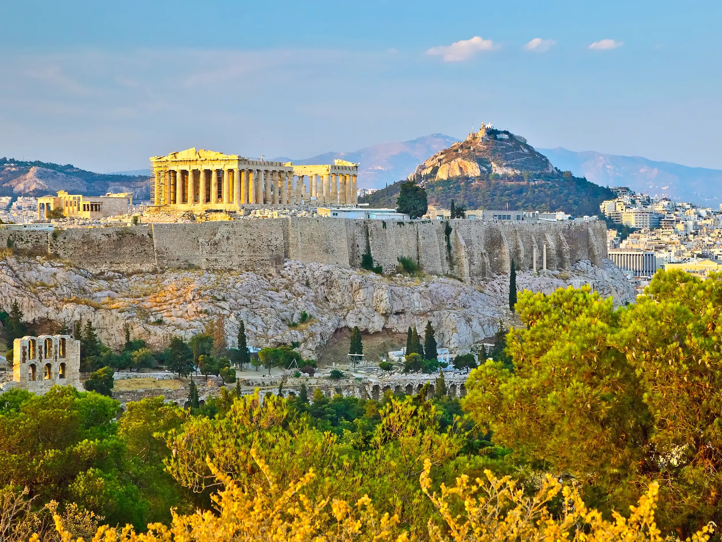 Die Akropolis in Athen im warmen Abendlicht, im Hintergrund der Likavittoshügel über dem Häusermeer der Stadt.