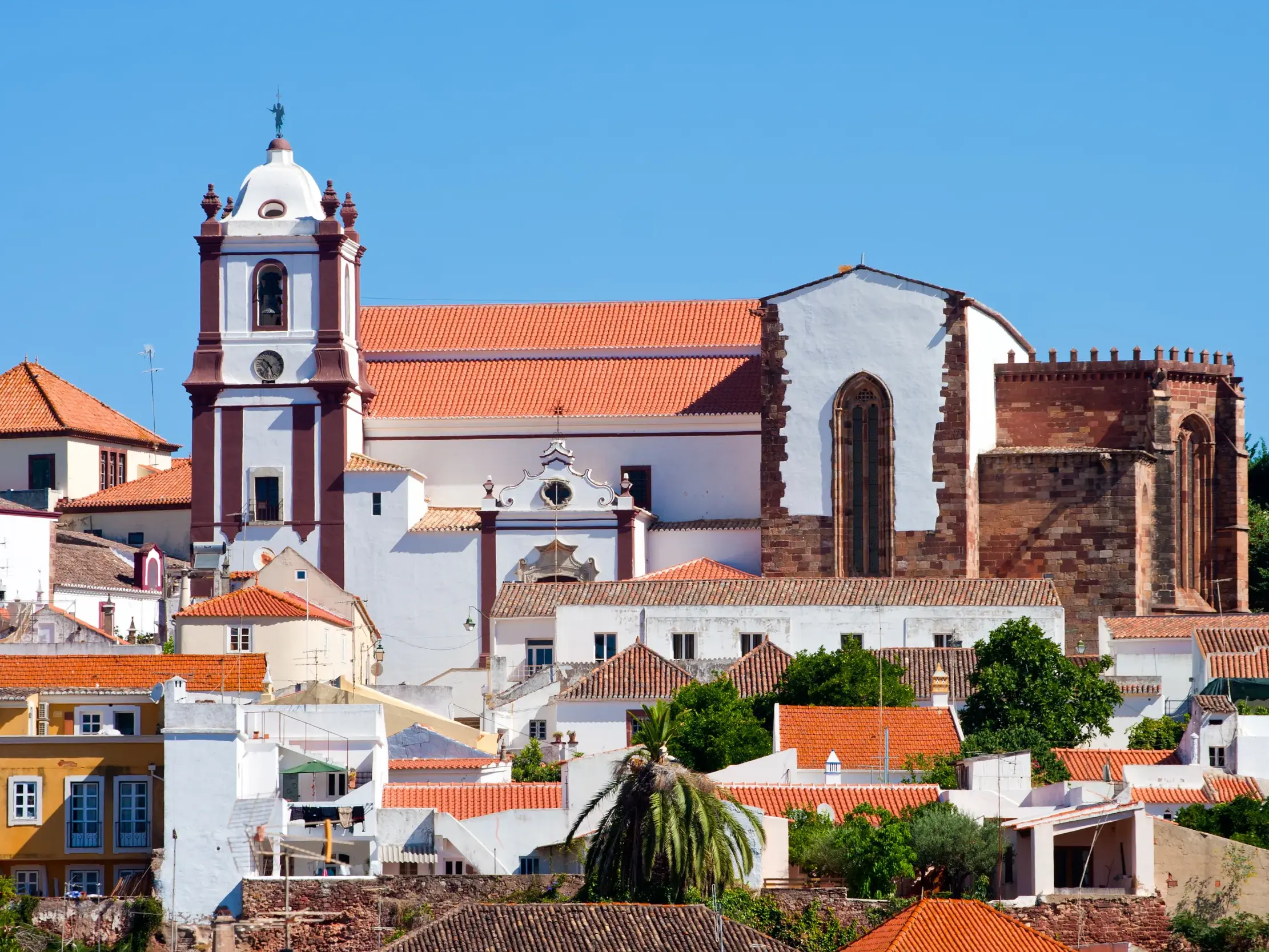 Blick auf die gotische Kathedrale von Silves und die weißen Häuser der Altstadt bei einer Wanderreise an der Algarve.