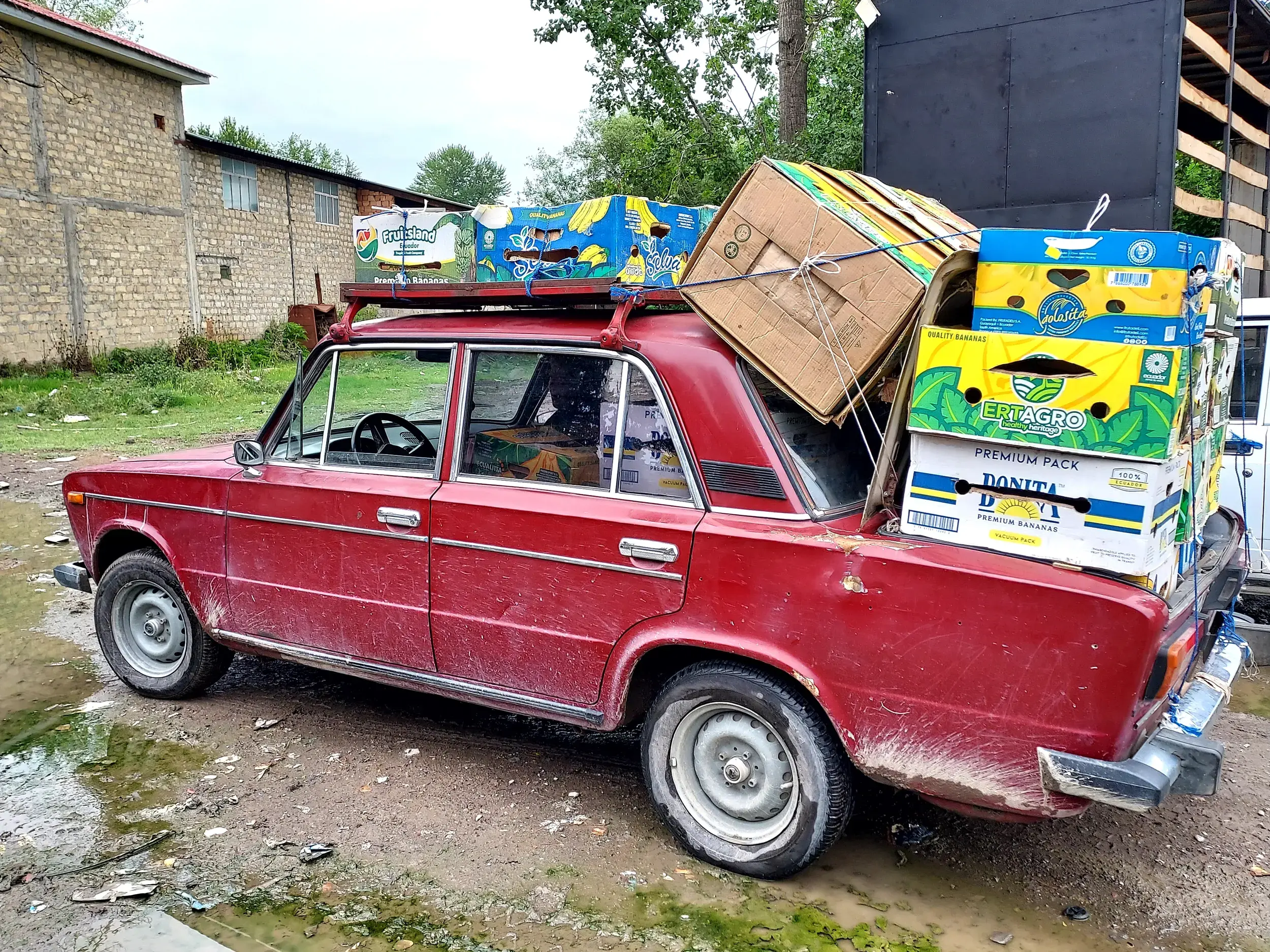 Ein alter, schmutziger Lada, voll beladen mit Obstkisten auf dem Dach und Kofferraum, in einem Dorf in Aserbaidschan.