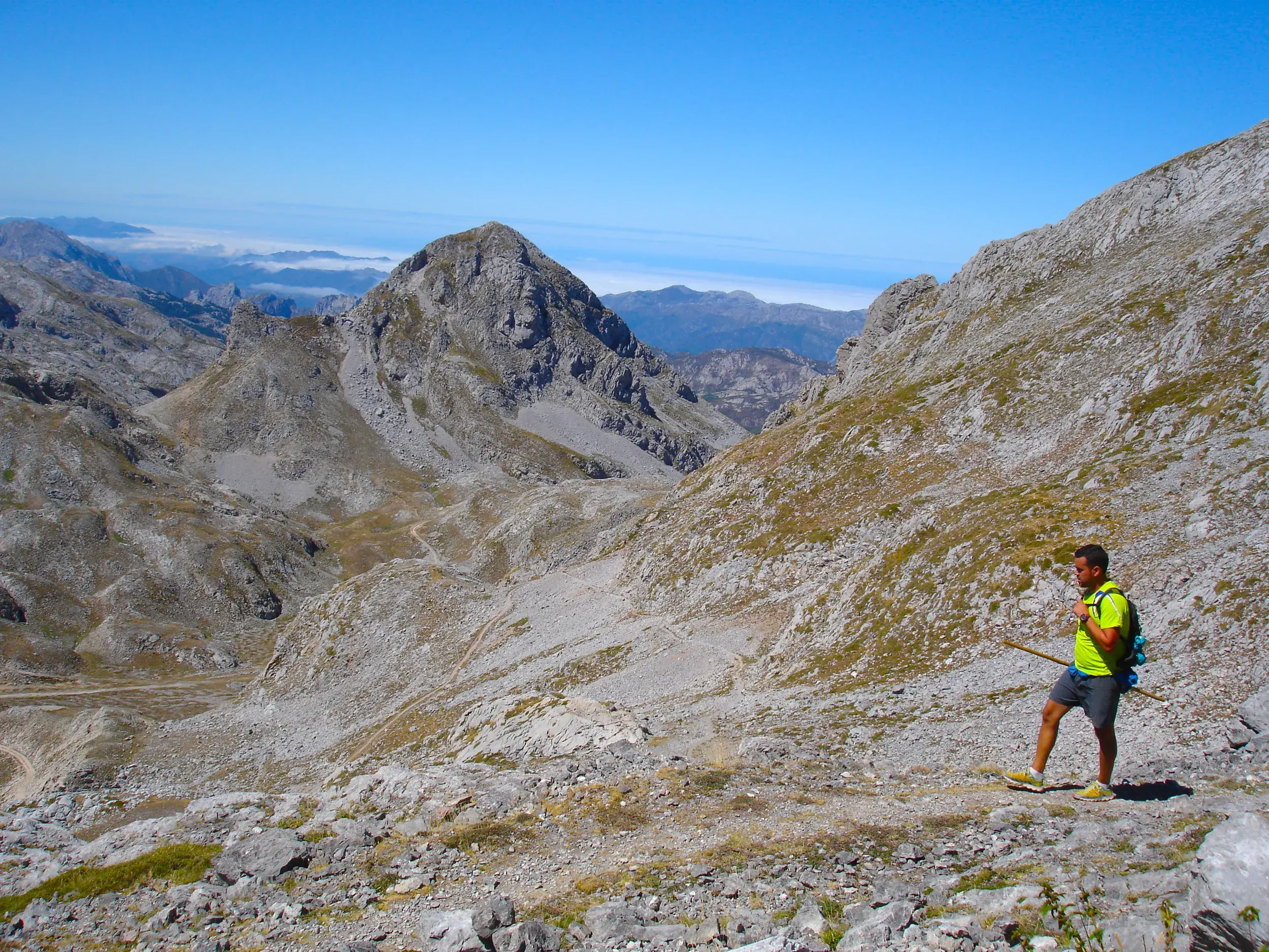 Ein Wanderer mit Rucksack erkundet auf einem felsigen Pfad die karge Berglandschaft des Ándara-Massivs in den Picos de Europa.