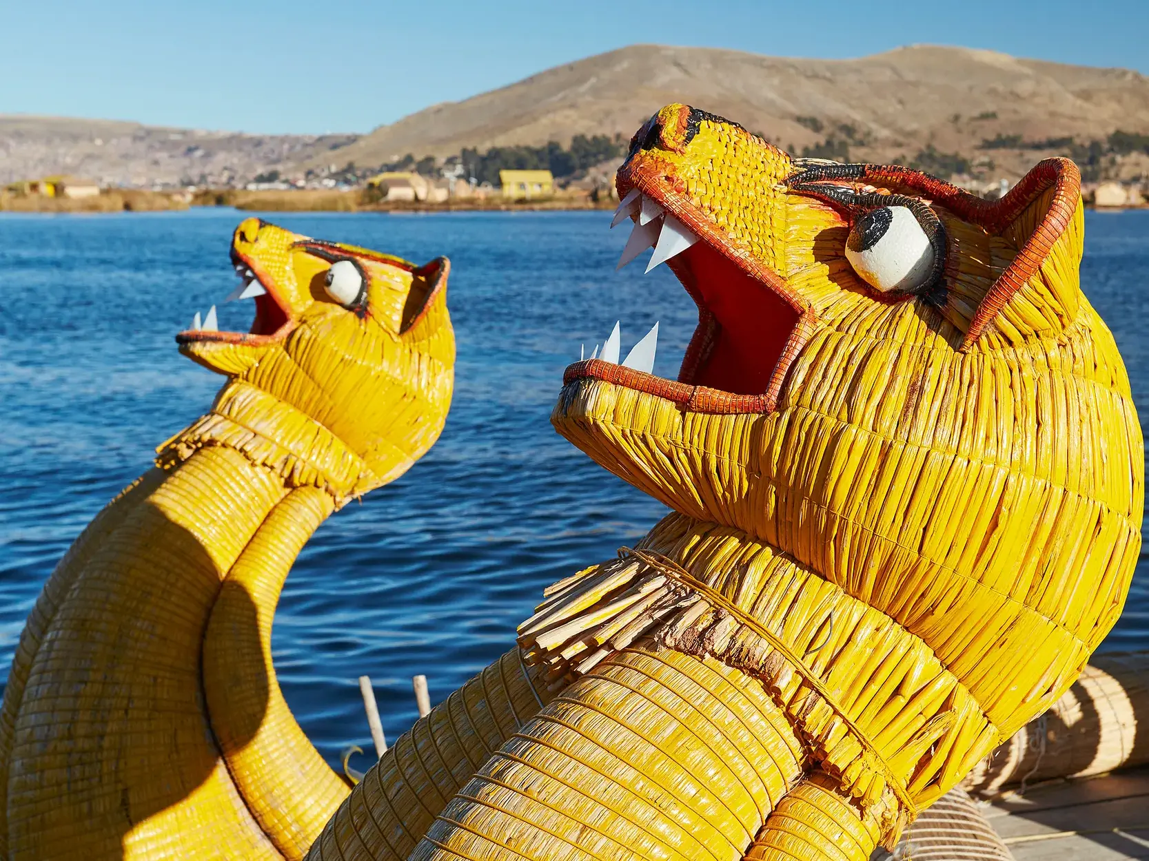 Kunstvolle Drachenköpfe eines Totora-Bootes auf einer Studienreise über den tiefblauen Titicacasee in den Anden.