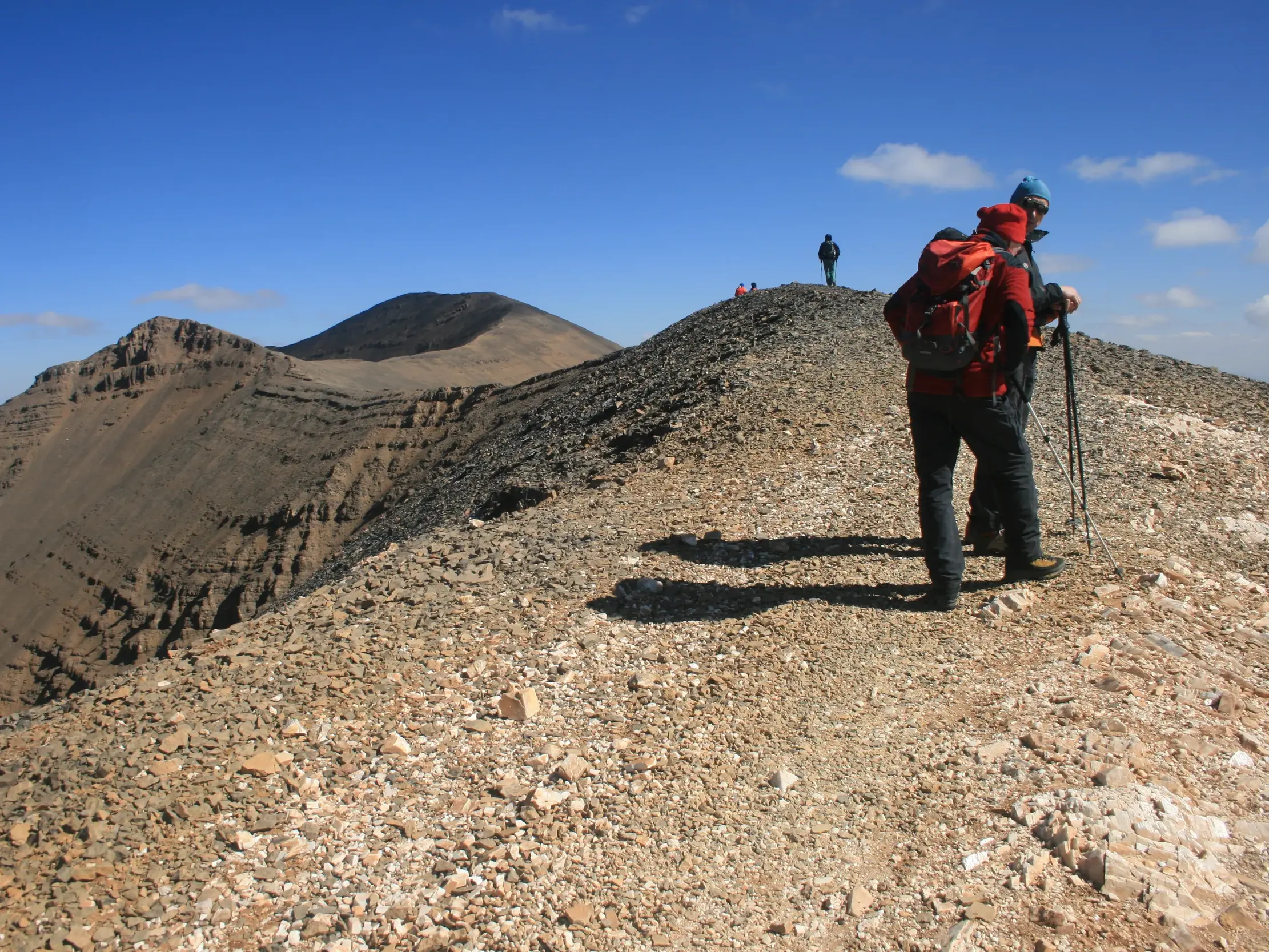 Trekkinggruppe auf dem schmalen Panoramakamm des Ighil Mgoun mit weitem Blick über das karge Mgoun-Massiv in Marokko.