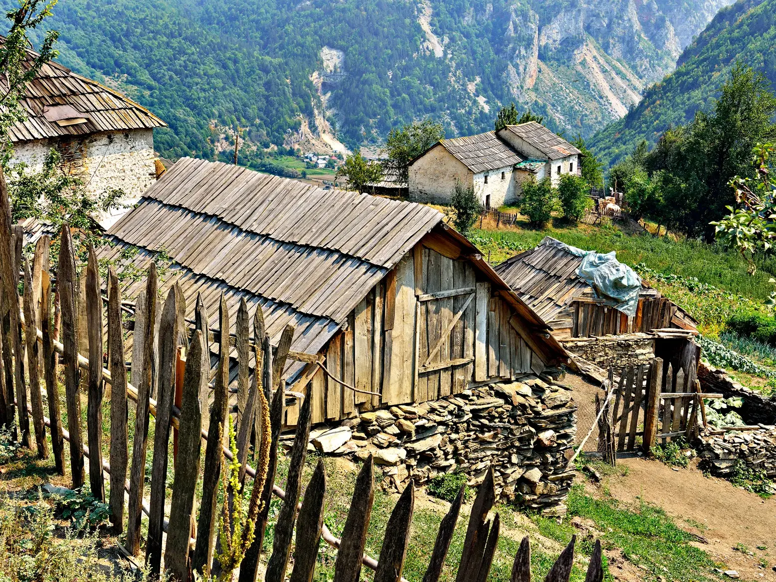 Traditionelle Berghütten und ein Holzzaun in einem abgeschiedenen Dorf auf der Trekkingreise Peaks of the Balkans.