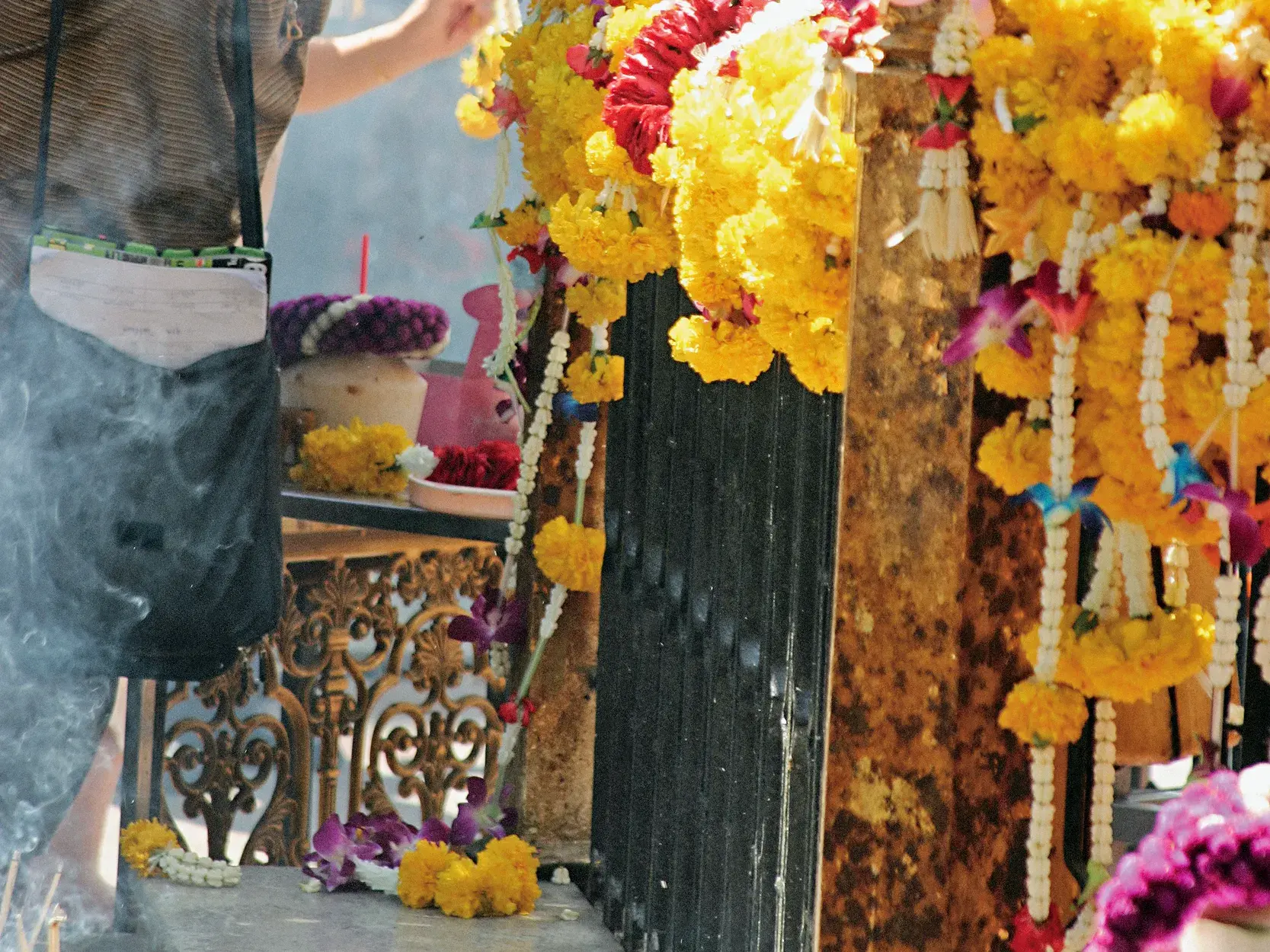 Authentische Szene in einem Tempel in Thailand: Gelbe Blumengirlanden und Weihrauch als spirituelle Opfergabe.