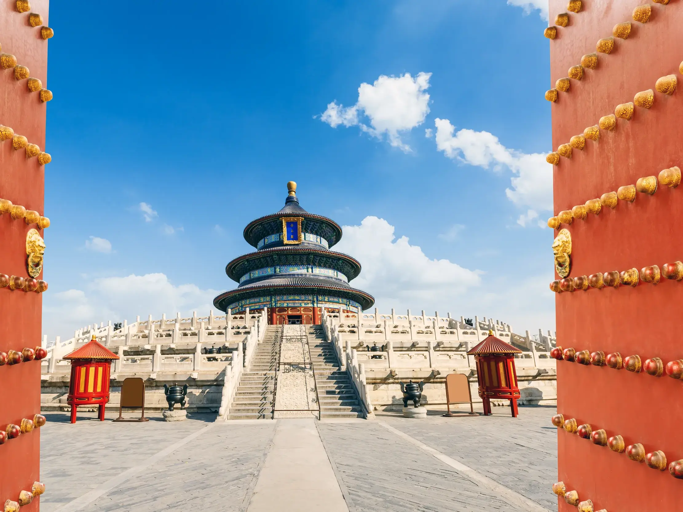 Blick durch ein rotes Tor auf den historischen Himmelstempel in Beijing bei strahlend blauem Himmel.